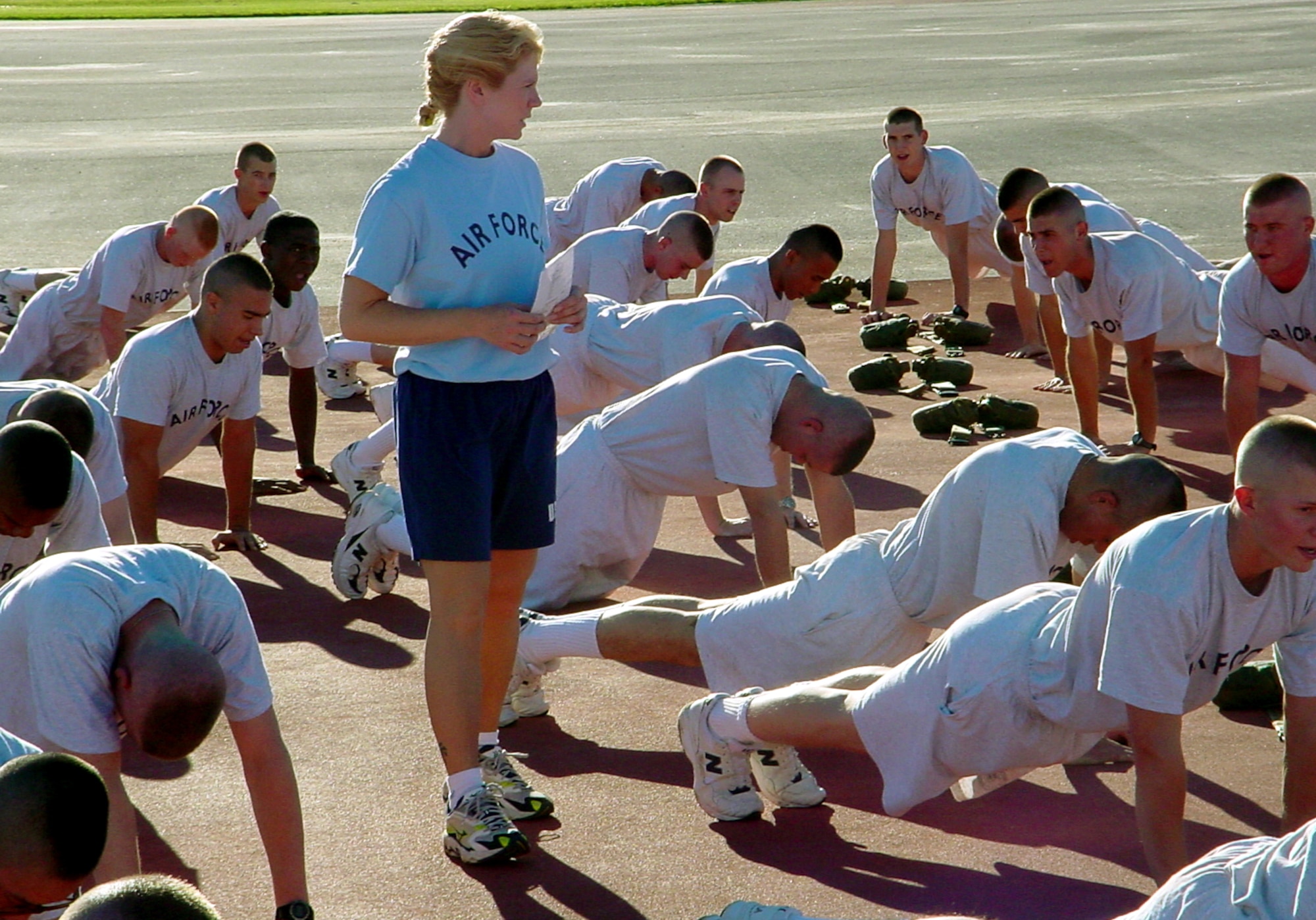 LACKLAND AIR FORCE BASE, Texas -- Staff Sgt. Dawn Adams (standing), a military training instructor with the 331st Training Squadron here, monitors trainees' pushups during physical readiness training.  New graduation standards for physical fitness take effect in basic training Oct. 12.  (Courtesy photo)