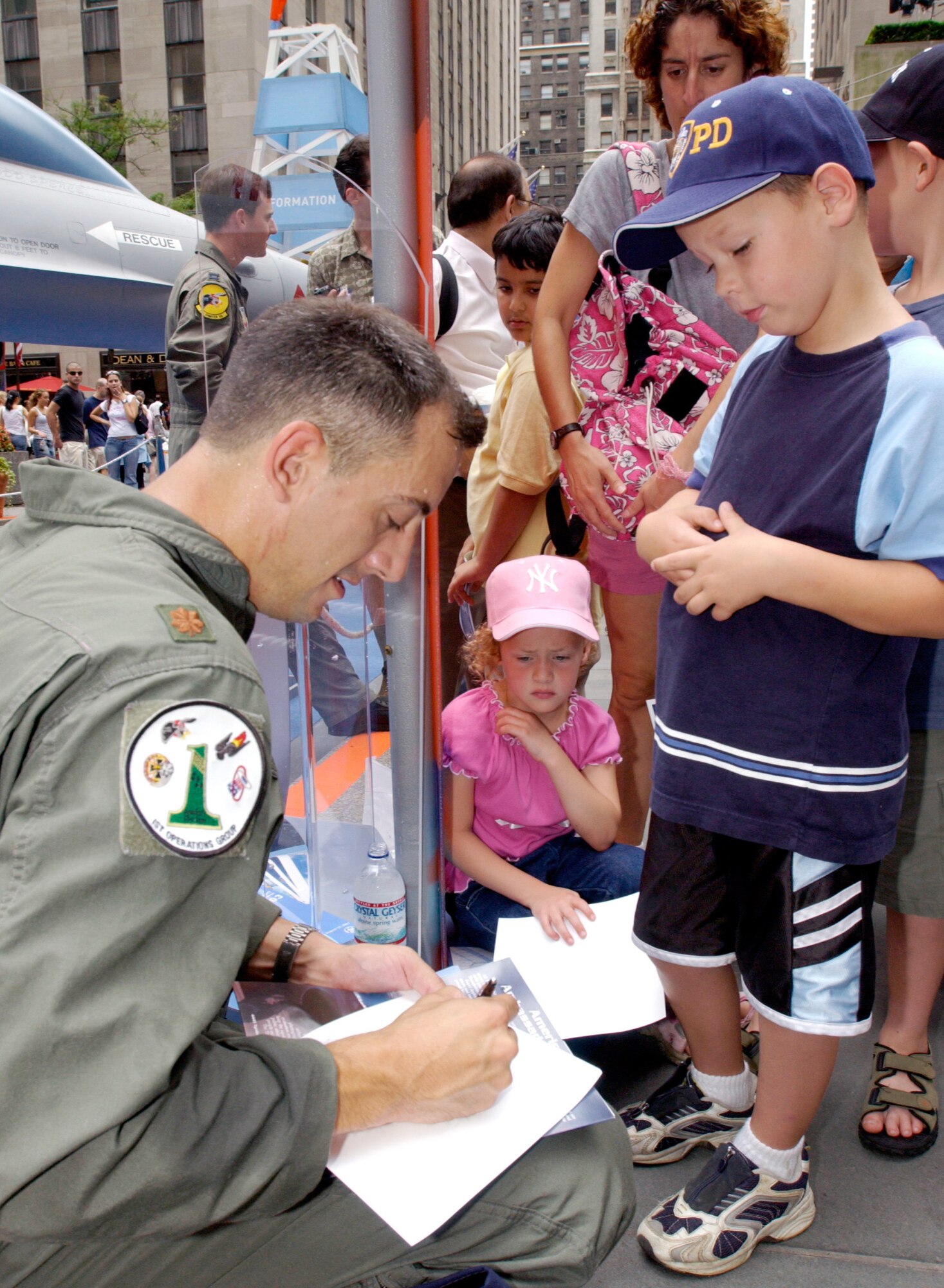 NEW YORK -- Maj. Cory Bower signs an autograph for Harrison, age 6, during a Centennial of Flight celebration Aug. 9 at Rockefeller Center here.  Bower is an F-15 Eagle pilot assigned to the 27th Fighter Squadron at Langley Air Force Base, Va.  (U.S. Air Force photo by Staff Sgt. A.J. Bosker)