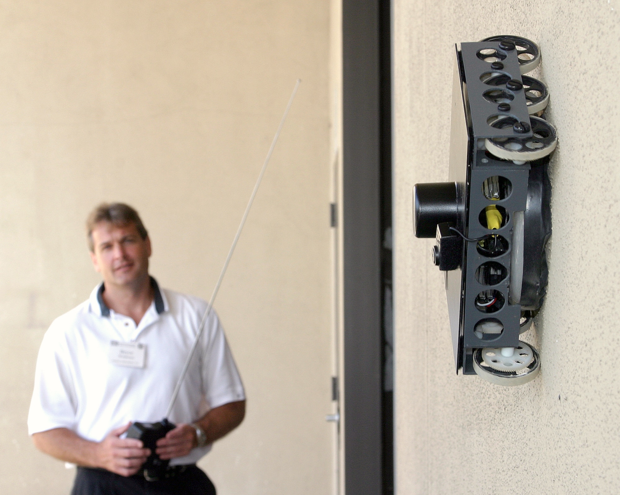 SAN ANTONIO -- Bryce Wiedeman motors a six-wheeled robot along a wall by remote control during the Lackland Force Protection Battlelab Exposition on Aug. 6 at the Southwest Research Institute here.  A process called "vortex attraction" that works in both air and water holds the robot to the wall.  (U.S. Air Force photo by Robbin Cresswell)