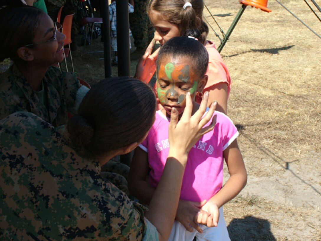 Marines from the 6th Communication Battalion give out free camouflage makeovers for children at their annual Family Day recently.  Marines and their families received information on benefits and were treated to a barbeque, relay races, games and equipment displays.