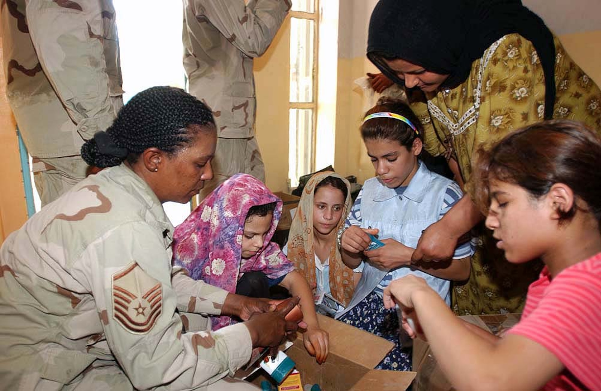 AN NASIRIYAH, Iraq -- Master Sgt. Sylvia Goodwin helps local children sort through the contents of one of the boxes delivered to local orphanages. She is the 332nd Expeditionary Communications Squadron's post office postmaster.  Airmen and soldiers from nearby Tallil Air Base delivered supplies to the orphans as part of a local volunteer initiative.  (U.S. Air Force photo by Staff Sgt. John Barton)
