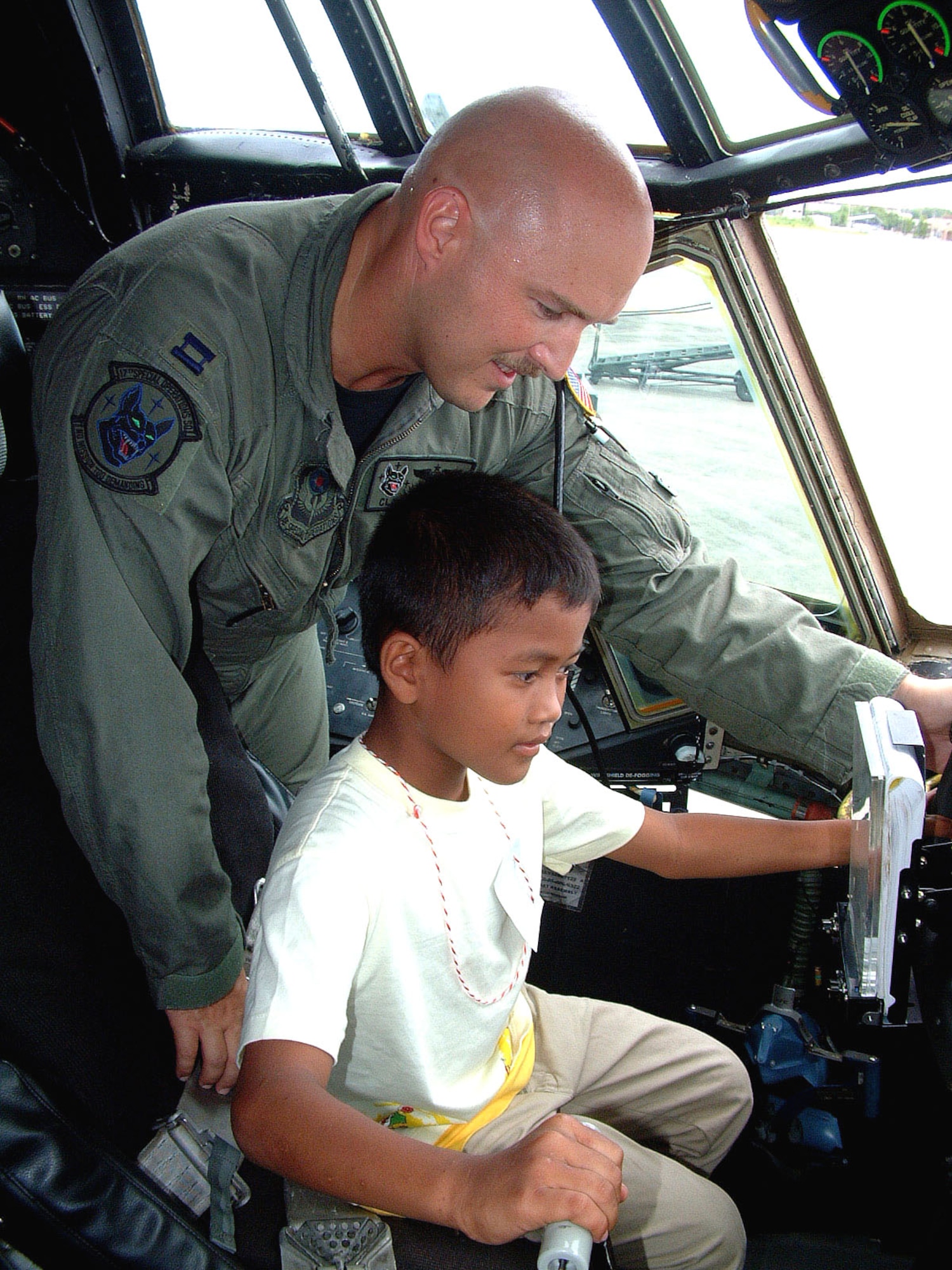 U-TAPAO AIR BASE, Thailand -- Capt. Clark Olander shows children from a nearby orphanage around the cockpit of an MC-130P Combat Shadow.  Olander is a 17th Special Operations Squadron navigator from Kadena Air Base, Japan.  His team is deployed here to train with other U.S. and Thai special operations forces.  (U.S. Air Force photo by Master Sgt. Michael Farris)