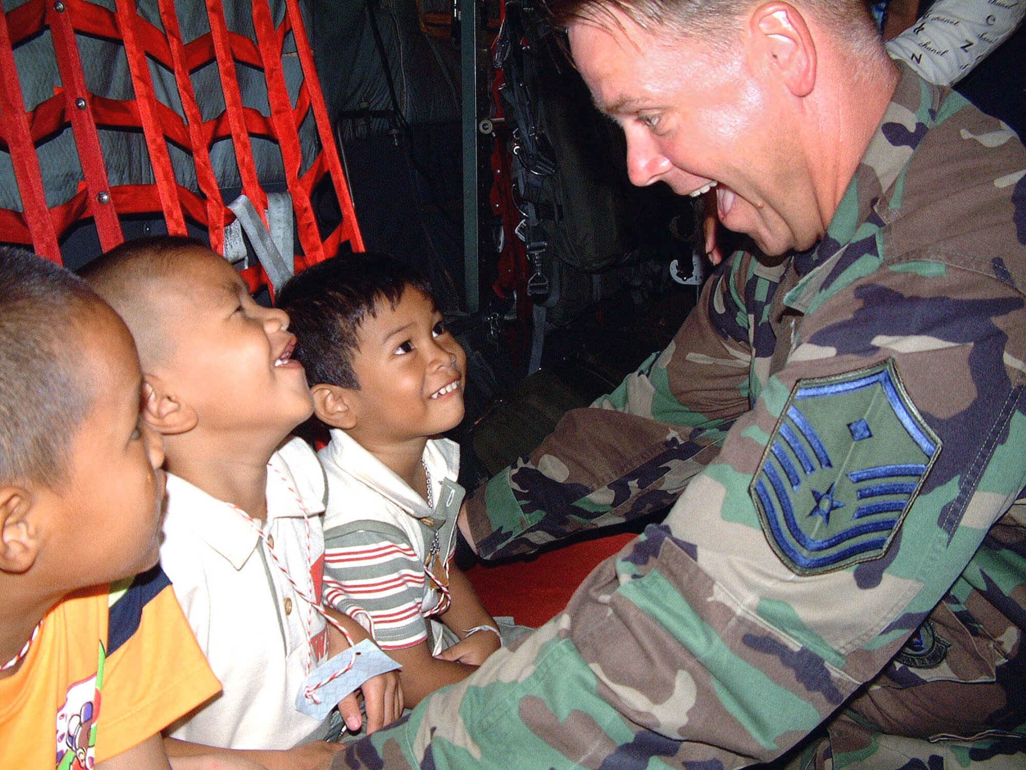 U-TAPAO AIR BASE, Thailand -- Master Sgt. James Johns shows children from a nearby orphanage how to buckle into an MC-130P Combat Shadow.  Johns is the first sergeant for the 17th Special Operations Squadron from Kadena Air Base, Japan.  His team is deployed here to train with other U.S. and Thai special operations forces.  (U.S. Air Force photo by Master Sgt. Michael Farris)