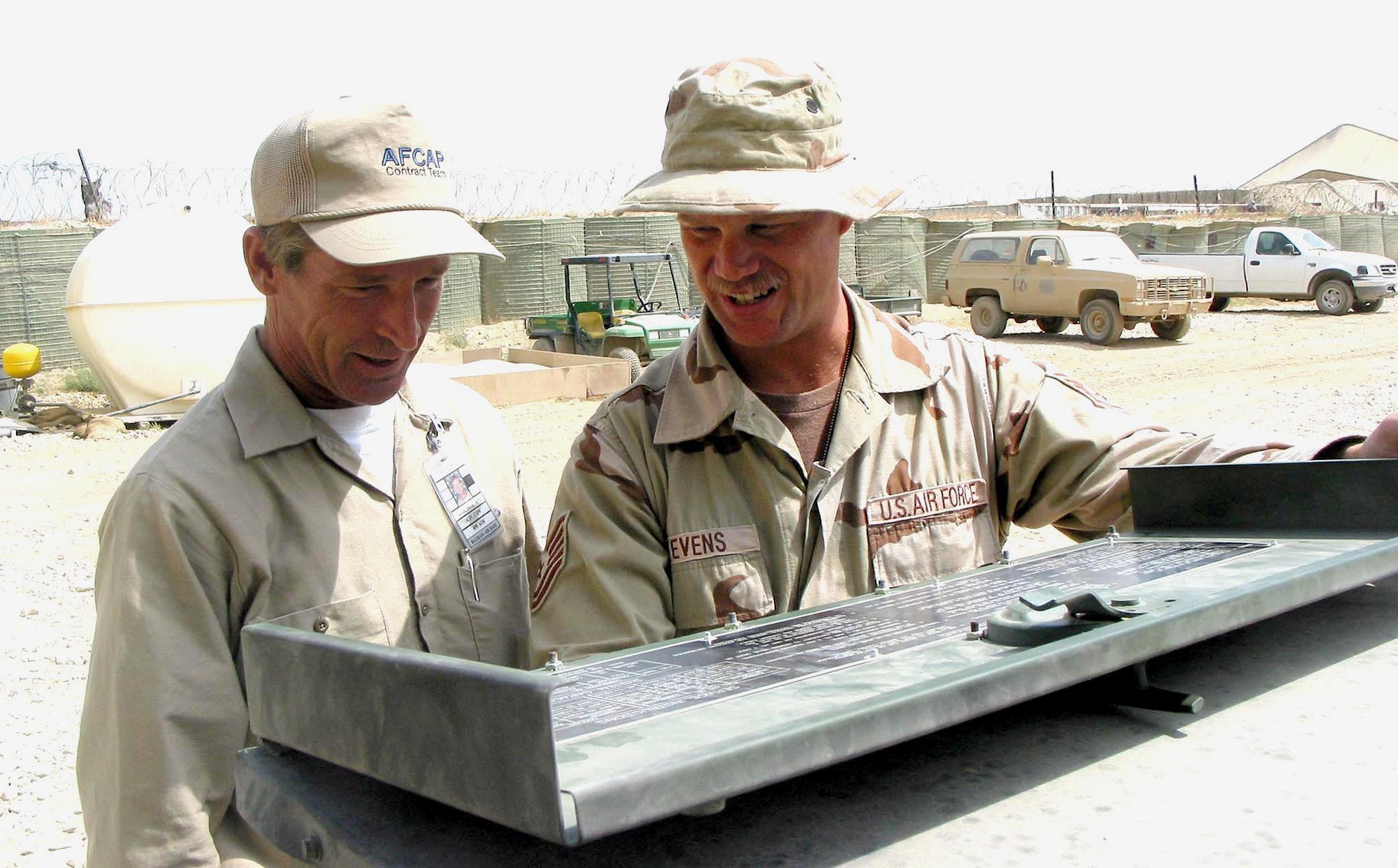 BAGRAM AIR BASE, Afghanistan - Contractor David Saville and Tech. Sgt. Lee Stevens review procedures for the power generator that feeds the air traffic control tower here.  Saveille will replace Stevens in September.  (U.S. Air Force photo by Staff Sgt. Russell Wicke)