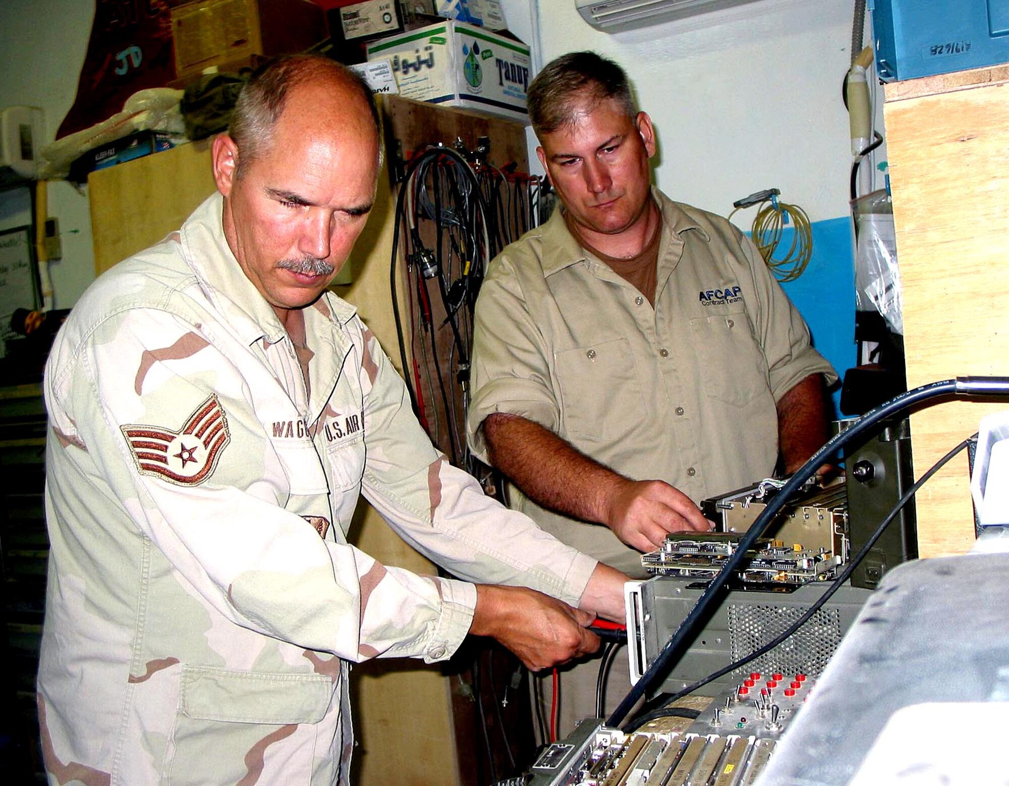 BAGRAM AIR BASE, Afghanistan - Staff Sgt. Brian Waggoner (left), 455th Airfield Operations Squadron, shows contractor Jeff Bryant the RT1319 radio used in the control tower here.  They are troubleshooting a maintenance problem with the radio used to talk to aircraft.  Bryant will replace Waggoner in September.  (U.S. Air Force photo by Staff Sgt. Russell Wicke)