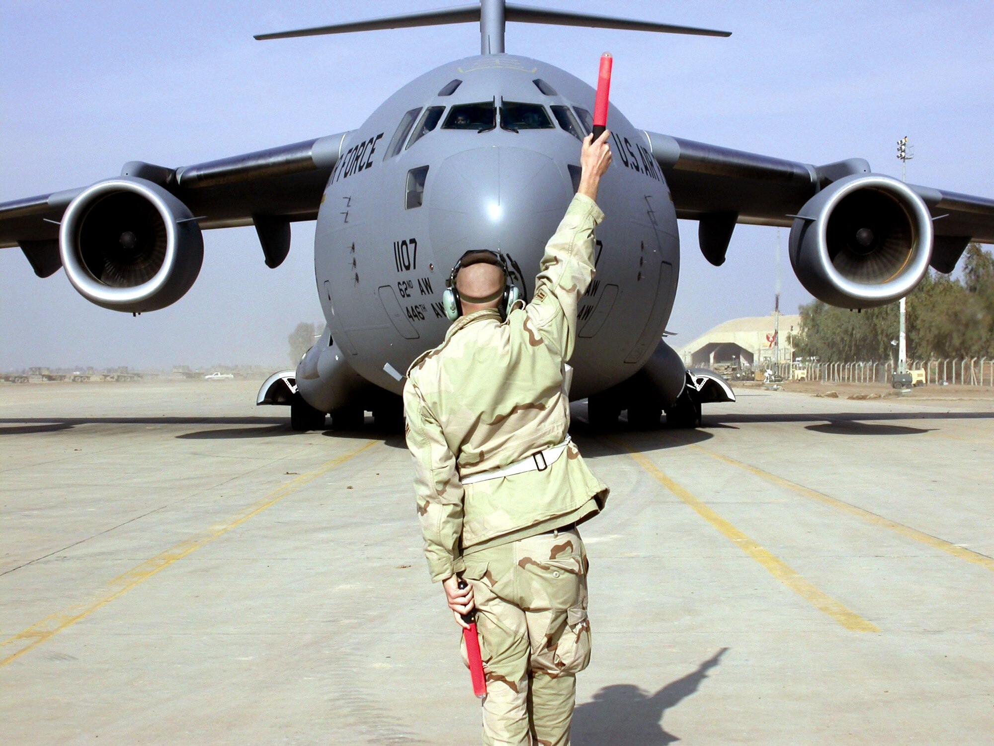 BALAD AIR BASE, Iraq -- Airman 1st Class James Amelung marshals a C-17 Globemaster III from McChord Air Force Base, Wash., to its parking spot here.  As many as 30 cargo aircraft arrive here each day. Amelung is assigned to the 332nd Air Expeditionary Aircraft Maintenance Squadron.  (U.S. Air Force photo by Staff Sgt. A.C. Eggman)