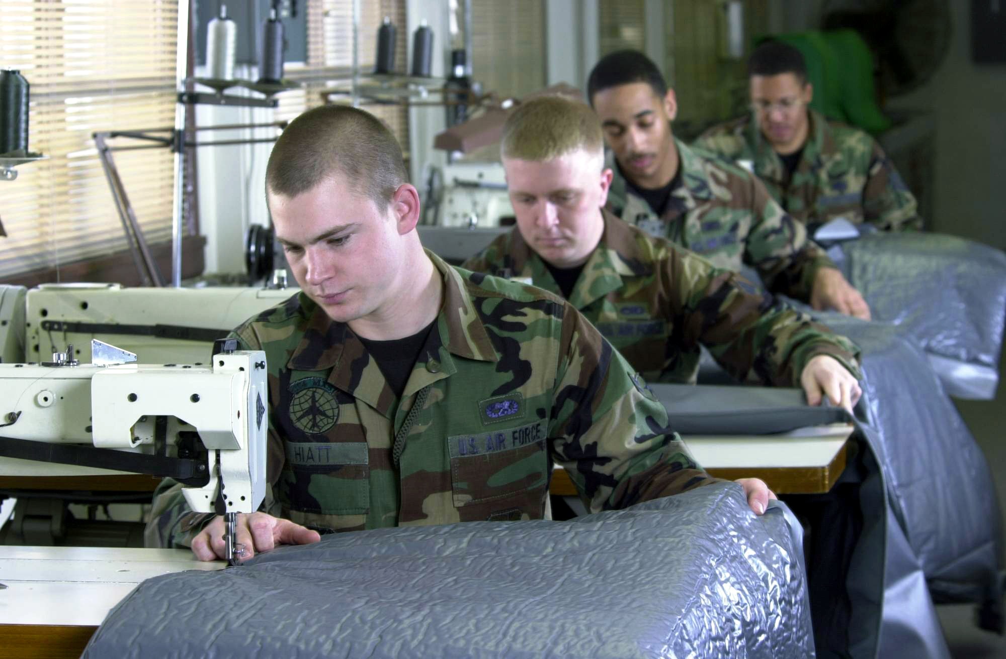 YOKOTA AIR BASE, Japan -- (Front to back) Airman 1st Class Brian Hiatt, Senior Airman Kyle Richardson, Aiman Mark McMorris and Staff Sgt. Sam Farrell sew aircraft insulation pieces..  The airmen are replacing the green C-130 Hercules aircraft interior insulation pieces here with the gray-colored ones during a refurbishing program.  The airmen are all survival equipment technicians from the 374th Maintenance Squadron.  (U.S. Air Force photo by Master Sgt. Val Gempis)