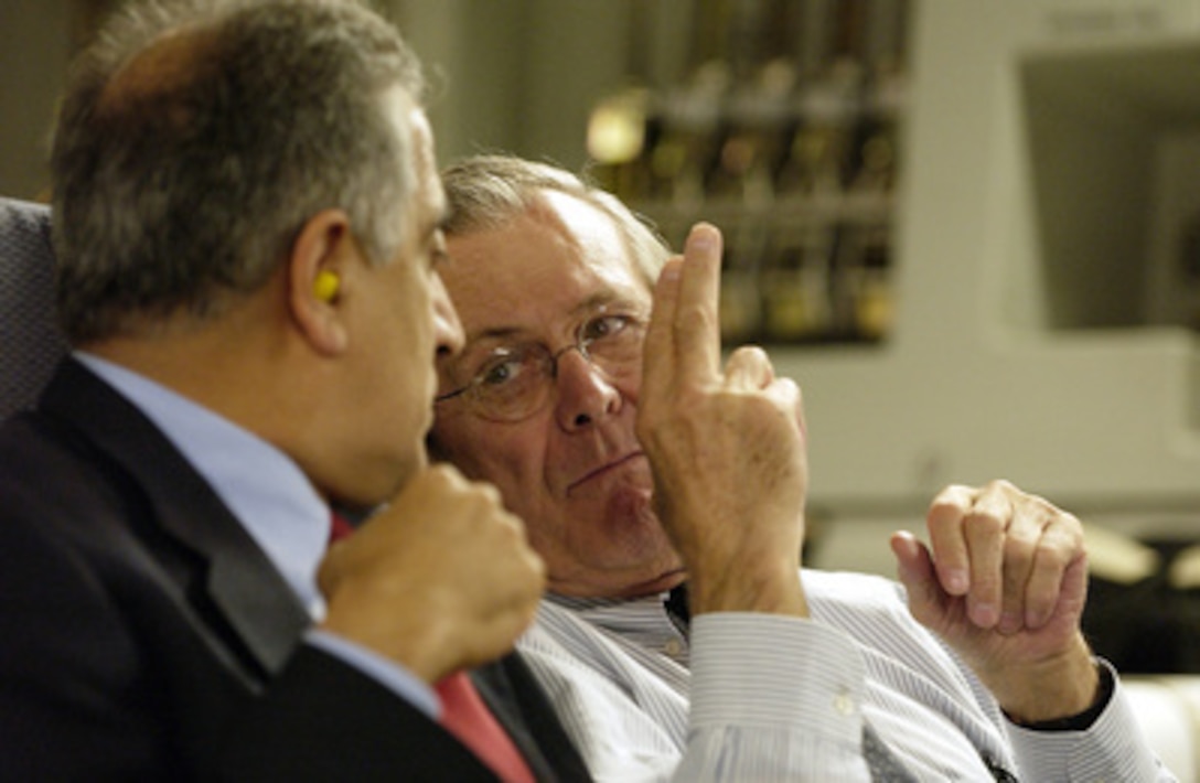 Secretary of Defense Donald H. Rumsfeld talks with U.S. Ambassador Zalmay M. Khalilzad onboard an Air Force C-17 Globemaster III en route to Kabul, Afghanistan, on Dec. 4, 2003. Rumsfeld is traveling to Afghanistan to meet with President Hamid Karzai and U.S troops deployed there. 