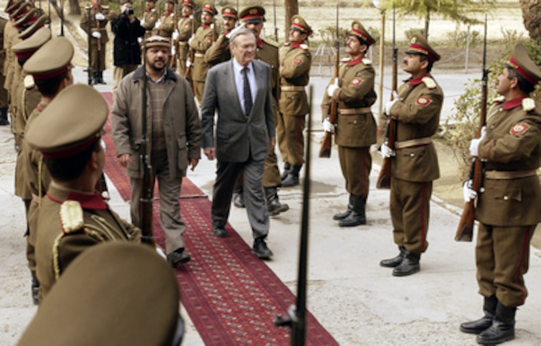 Afghanistan's Minister of Defense Mohammad Fahim Khan (left) escorts Secretary of Defense Donald H. Rumsfeld through an honor guard and into the Ministry of Defense headquarters for a meeting in Kabul, Afghanistan, on Dec. 4, 2003. Rumsfeld is in Afghanistan to meet with Khan, President Hamid Karzai, and U.S troops deployed there. 