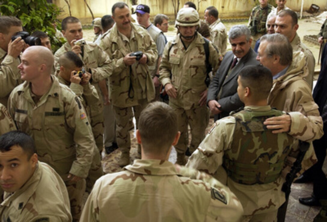 Secretary of Defense Donald H. Rumsfeld (right) poses for photos with some of the soldiers who took part in Operation Bayonet Lighting during his stop in Baghdad, Iraq, on Dec. 6, 2003. Rumsfeld is in Iraq to meet with members of the Coalition Provisional Authority, senior military leaders and the troops deployed there. 
