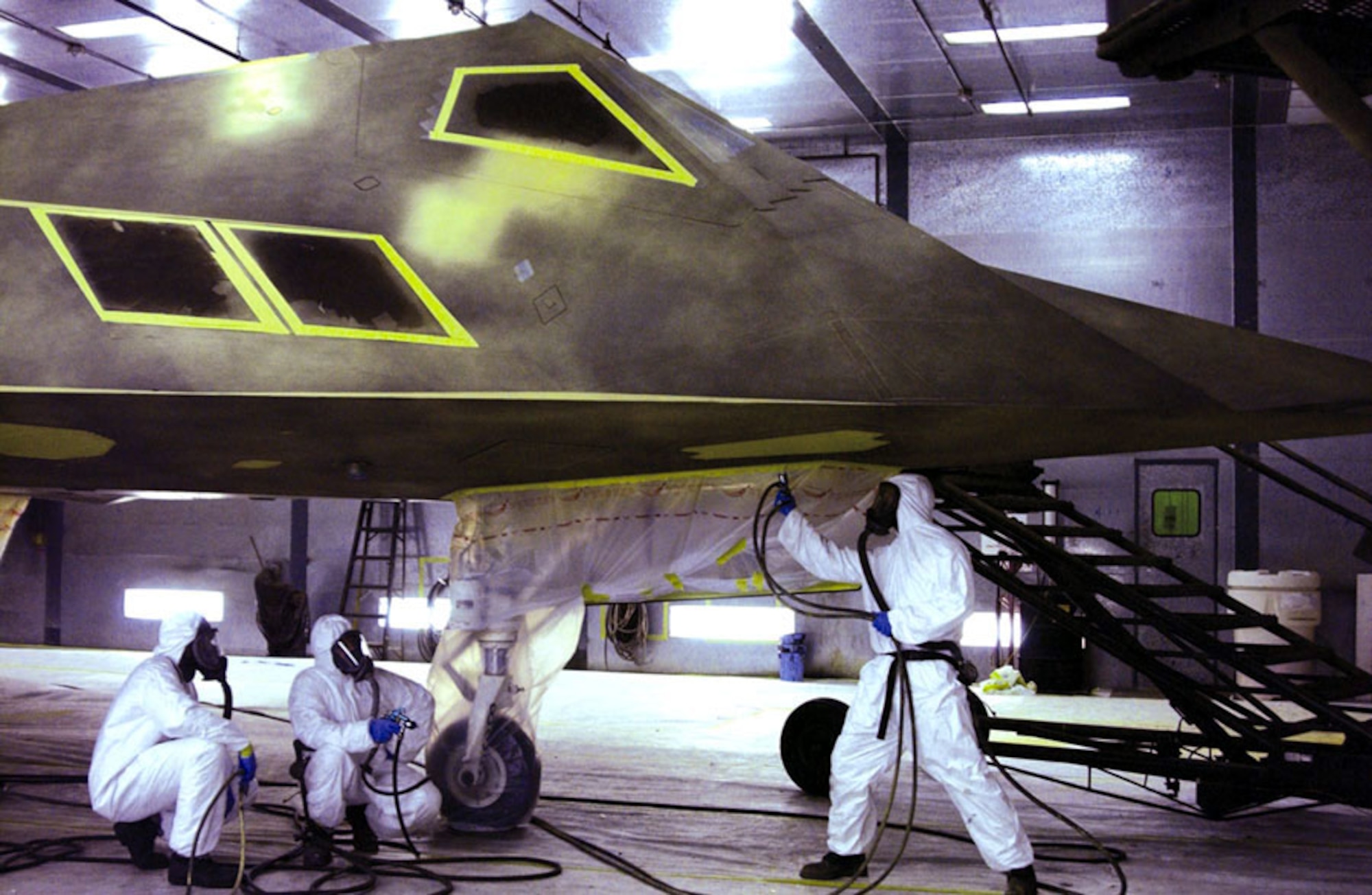 HOLLOMAN AIR FORCE BASE, N.M. -- (Left to right) Staff Sgts. Armond Cornin and Casell Davis, and Airman 1st Class Louis Delgado apply a layer of primer to the underbelly of an F-117 Nighthawk before it is painted gray.  The aircraft will participate in tests aimed at determining the feasibility of using the F-117 during daytime operations.  The airmen are assigned to the 49th Aircraft Maintenance Squadron here.  (U.S. Air Force photo by Airman 1st Class Vanessa LaBoy)