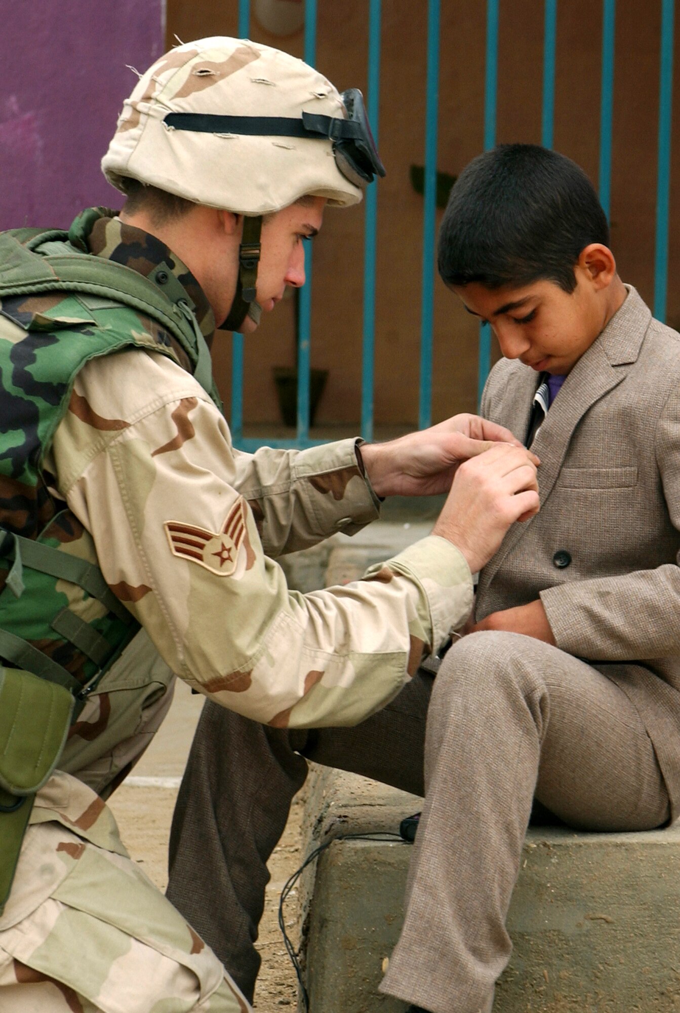 BAGHDAD, Iraq -- Senior Airman Brent Skeen fits an Iraqi student with a microphone for an interview after a ceremony to celebrate the reopening of a primary school here.  U.S. military broadcasters hit the airwaves here Dec. 10 with the first manned American Forces Radio and Television Service broadcast from the country.  Skeen is a broadcaster with American Forces Network-Iraq.  (U.S. Air Force photo by Tech. Sgt. John Houghton)