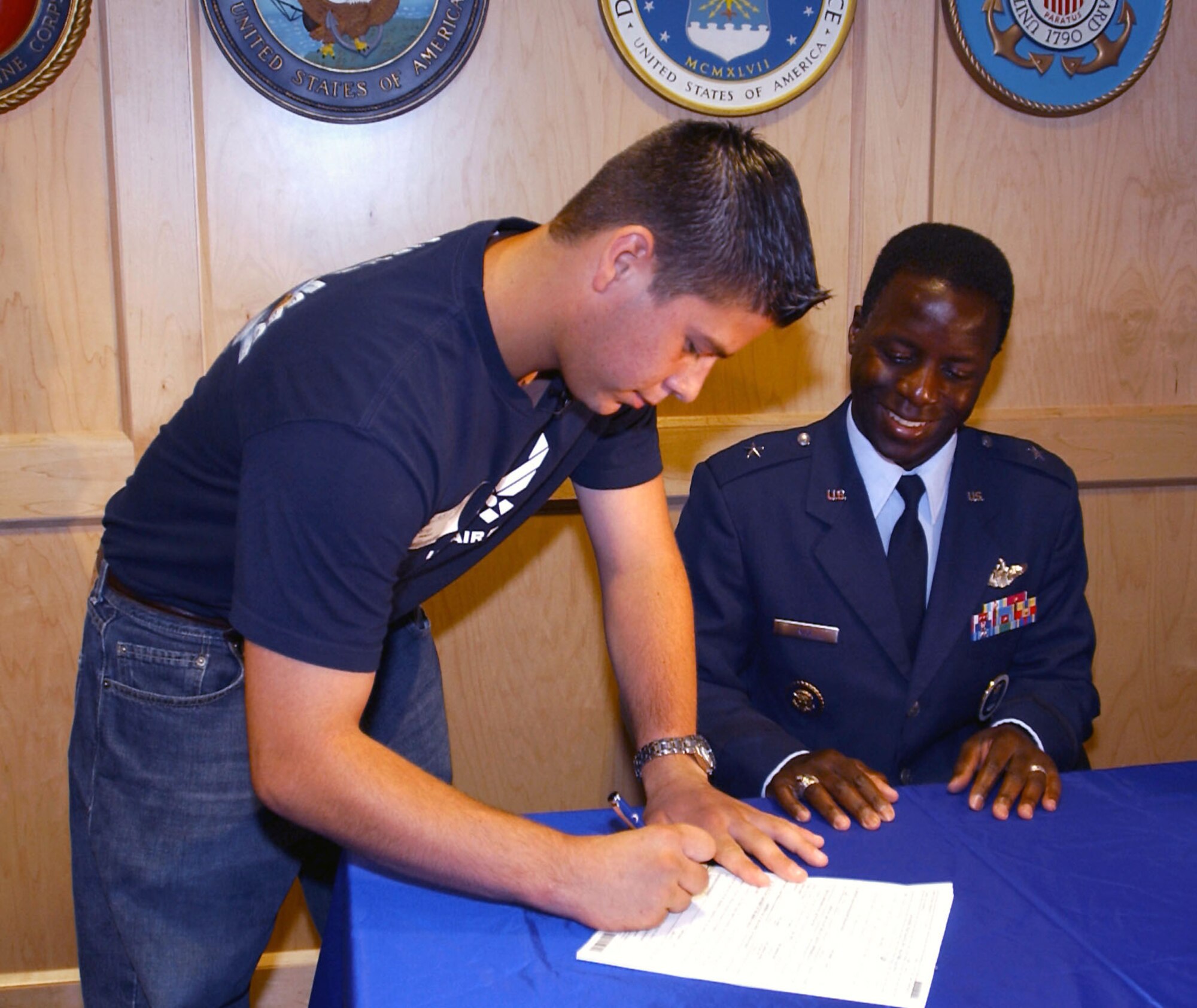 SAN ANTONIO -- Hector Baretto signs his Air Force enlistment contract, witnessed by Brig. Gen. Edward A. Rice Jr., Air Force Recruiting Service commander.  Baretto is the first Air Force 15-month enlistee under the National Call to Service program.  (U.S. Air Force photo by Angelica Delgado)