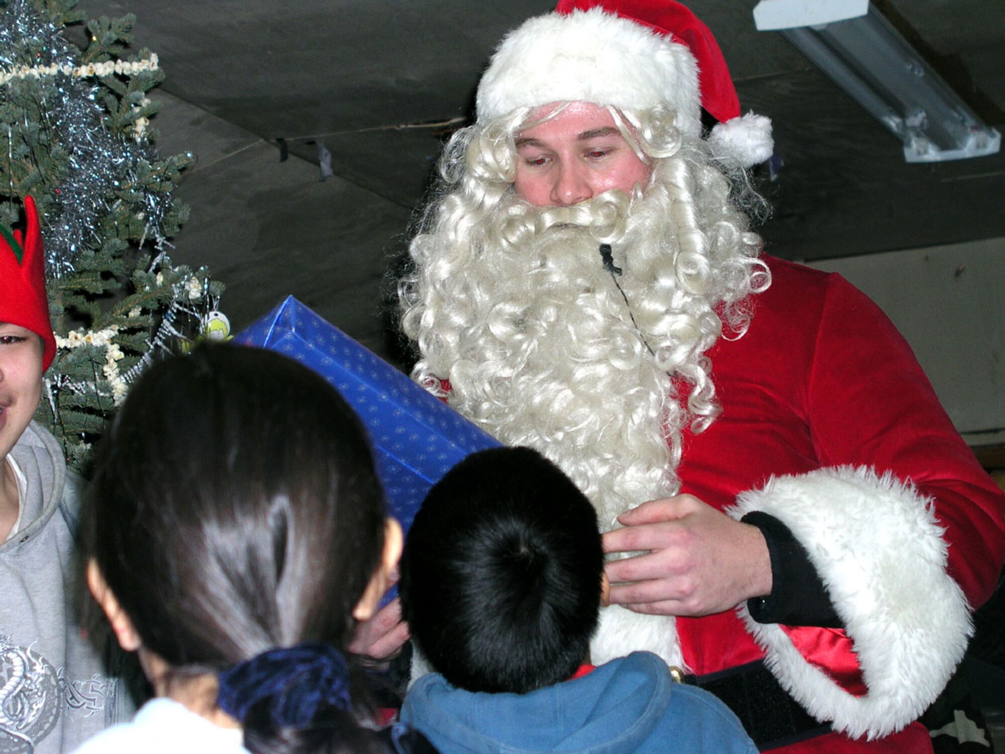 ARCTIC VILLAGE, Alaska -- Santa hands out Christmas gifts to the children here Dec. 15.  Airmen and their spouses from the 517th Airlift Squadron at Elmendorf Air Force Base, Alaska, visit the village every December to donate gifts, food and supplies.  (U.S. Air Force photo by Staff Sgt. Connie Bias)