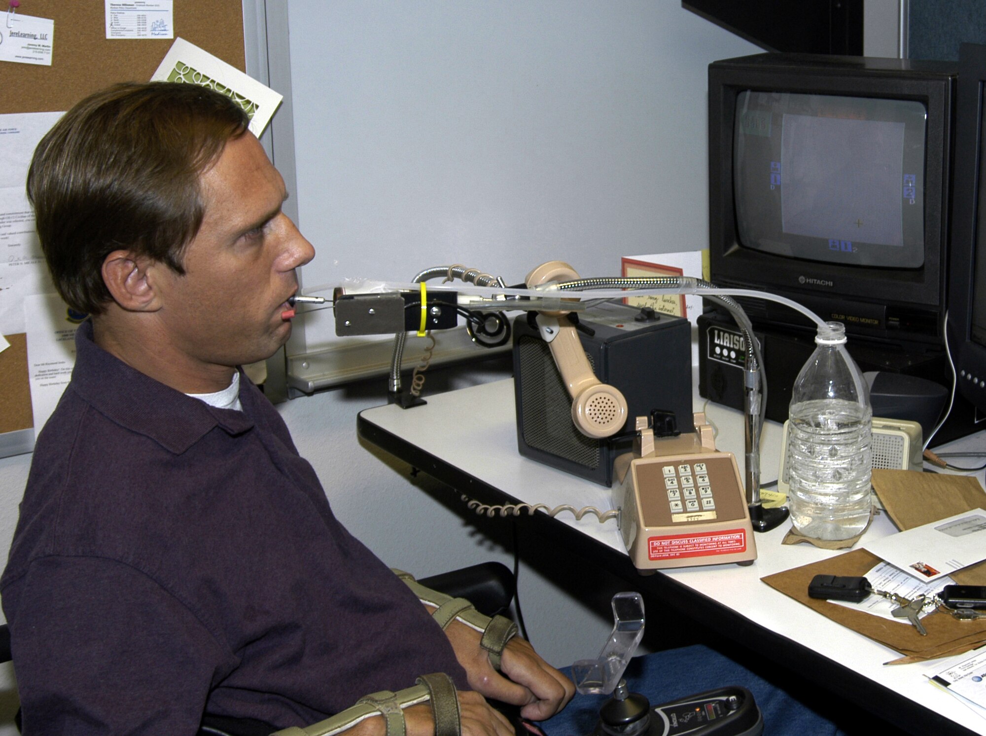 LACKLAND AIR FORCE BASE, Texas -- Raymond Jenks uses a computer-input device accessed by a chin controller.  The device allows him to answer and dial a telephone.  Jenks received the 2003 Outstanding Employee with a Disability Award.  He is an instructional systems specialist with the 37th Training Support Squadron here.  (U.S. Air Force photo by James Coburn)