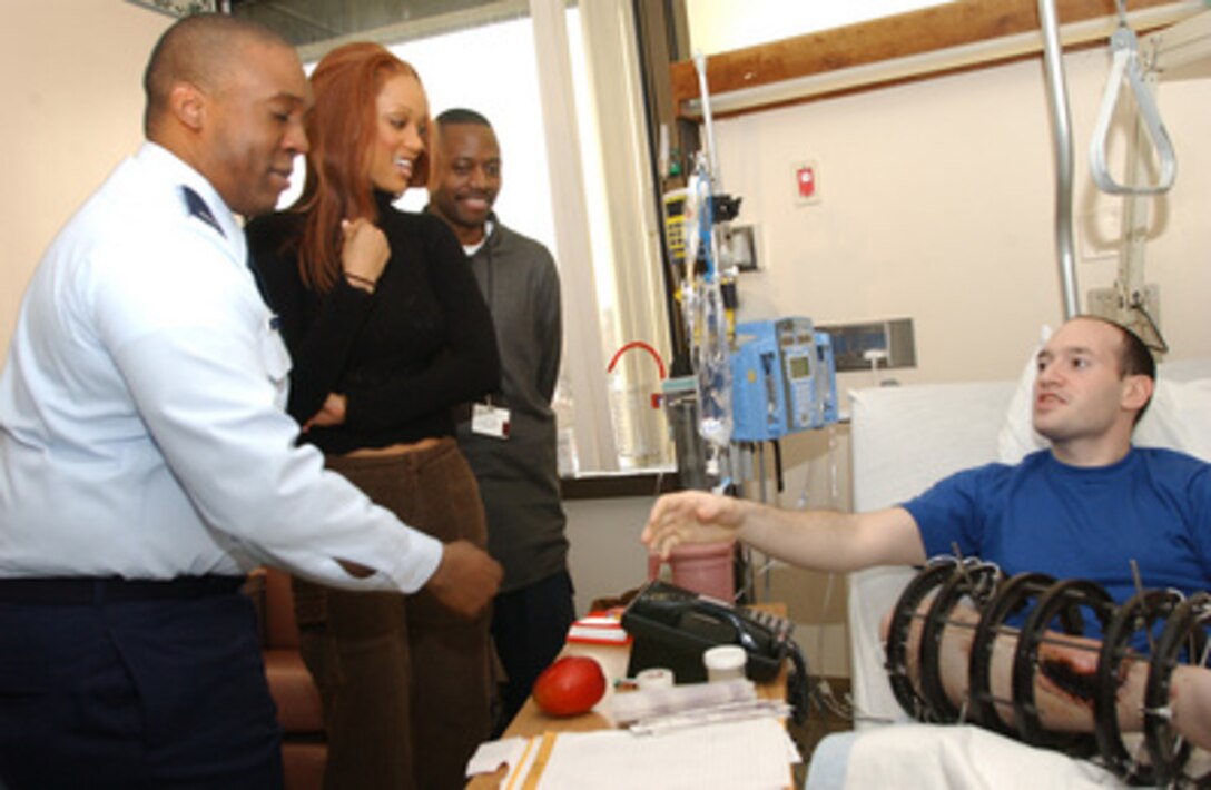 Tyra Banks (second from left) and her brother, Air Force 1st Lt. Devin Banks (left), visit with Army Pfc. Joseph Kashnow (right), a patient at Walter Reed Army Medical Center on Dec. 19, 2003. Banks, who considers the military a "personal family thing" due to her brother's 15 years of service, wanted to lift injured service members' spirits. 1st Lt. Banks is a contracting officer stationed at Bolling Air Force Base, Washington, D.C. 
