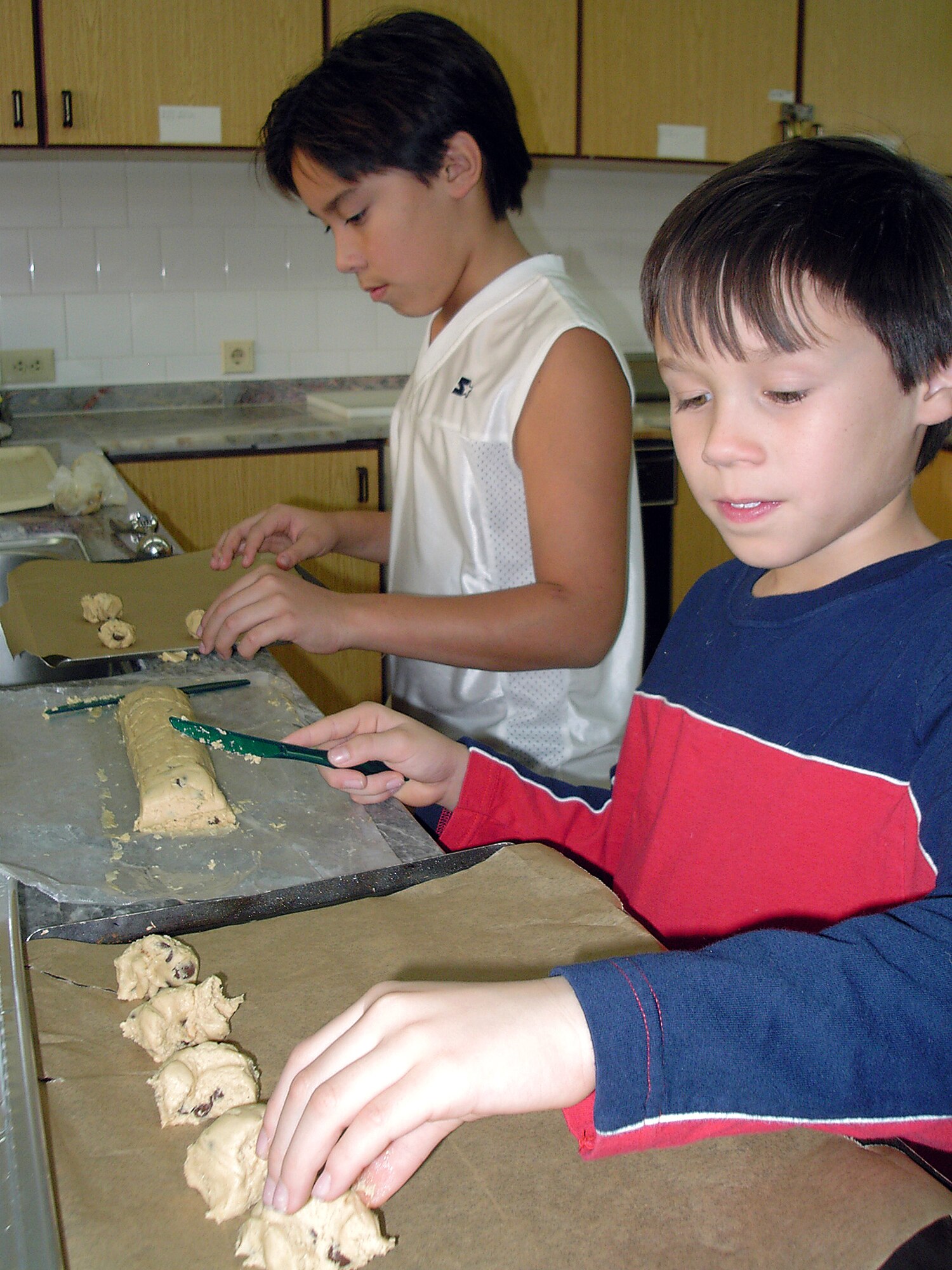 INCIRLIK AIR BASE, Turkey -- Dominic (left) and Jeremy Gonzaga, ages 11 and 9, make chocolate chip cookies for Operation C.H.I.P. (Cookies Help Incirlik Personnel).  The goal of the operation is to give every permanent-party and deployed unaccompanied airman a bag of home-baked cookies.   (U.S. Air Force photo by 2nd Lt. Elizabeth Culbertson)