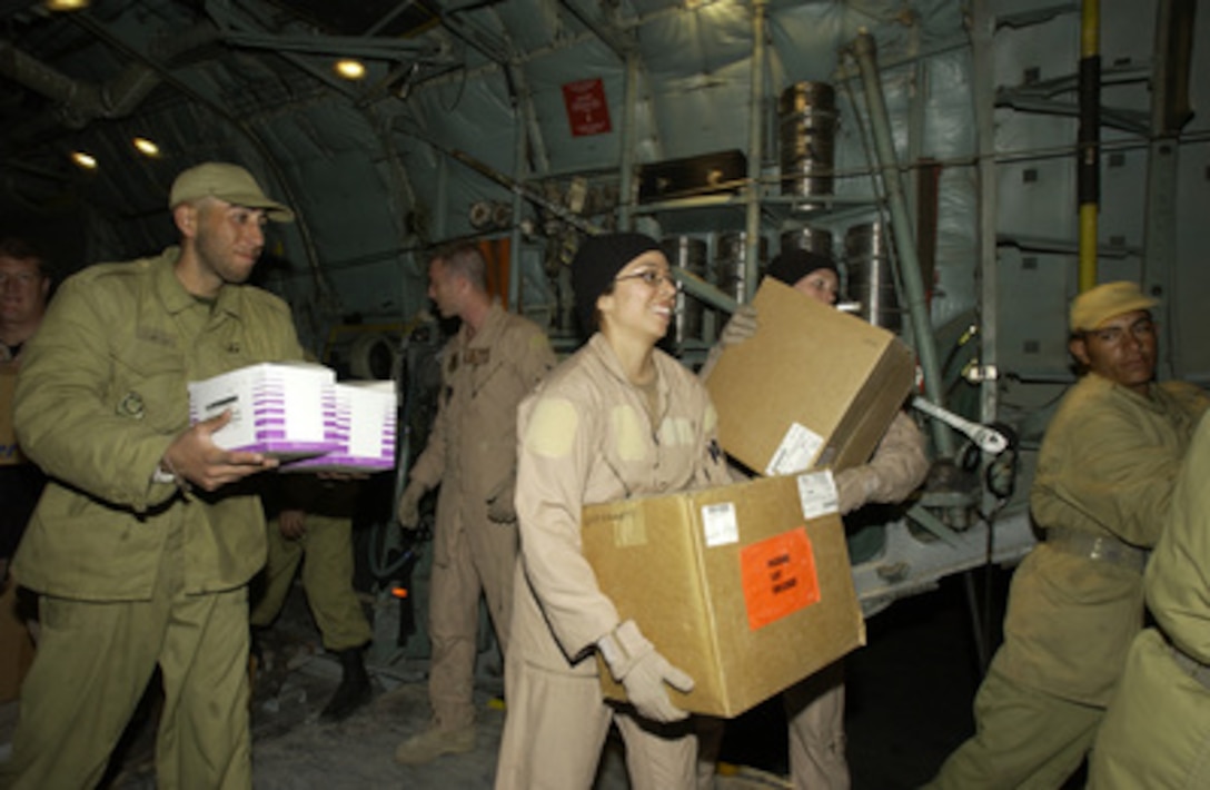 Staff Sgt. Samantha Yanez (center), of the 746th Expeditionary Airlift Squadron, carries a package from a U.S. Central Air Forces C-130 as part of a humanitarian relief mission to Kerman, Iran, on Dec. 28, 2003. The C-130 crewmembers and Iranian soldiers offloaded five pallets containing 20 thousand pounds of medical supplies at Kerman two days after a devastating earthquake destroyed the city of Bam, Iran. 
