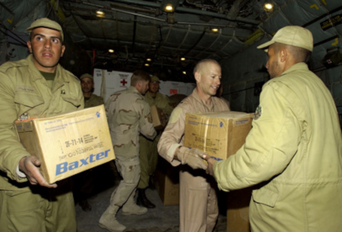 Lt. Col. Scot Decker (second from right), a C-130 aircraft commander, Iranian soldiers, and other Air Force personnel offload five pallets containing 20 thousand pounds of medical supplies at Kerman, Iran, on Dec. 28, 2003, two days after a devastating earthquake destroyed the city of Bam, Iran. 