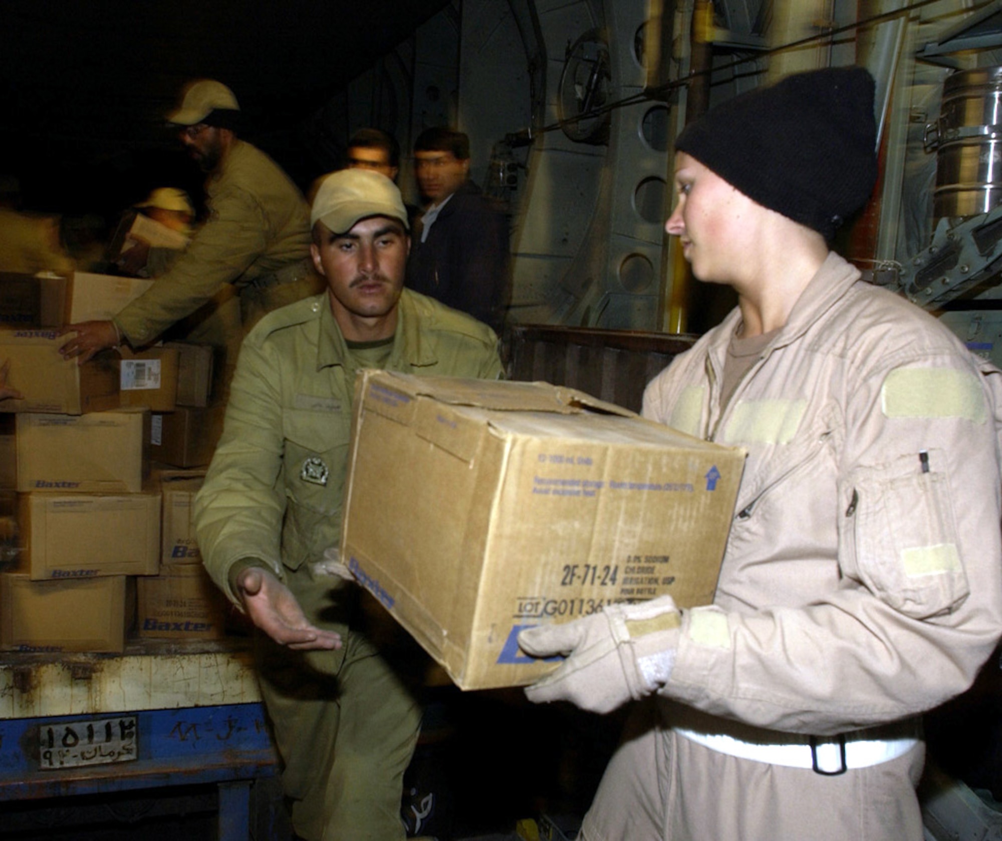 KERMAN, Iran -- Senior Airman Lindsey Whicker hands a box of water to an Iranian soldier here Dec. 28 as part of humanitarian relief efforts.  Whicker is assigned to the 746th Expeditionary Airlift Squadron and was part of a C-130 Hercules crew which airlifted 20 pallets of humanitarian supplies to Iran after an earthquake destroyed the city of Bam.  (U.S. Air Force photo by Staff Sgt. Suzanne M. Jenkins)