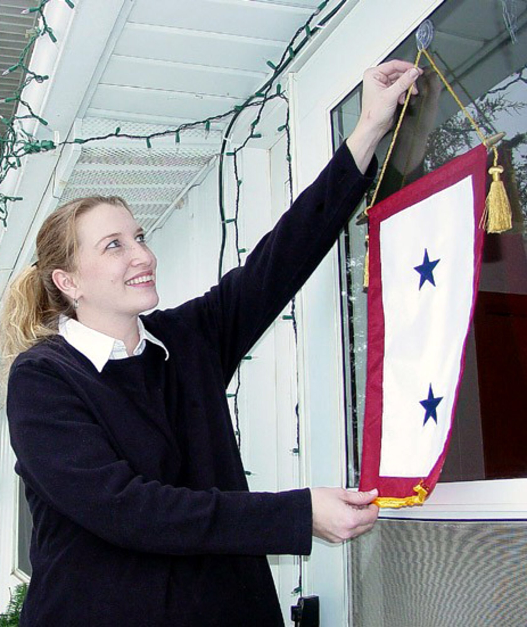 MINOT AIR FORCE BASE, N.D. -- Christa Wolfe, wife of 1st Lt. Marc Wolfe from the 741st Missile Squadron here, hangs a two-star service flag on her door. Christa's service flag honors her husband and her father, Lt. Col. Dennis McCarty, a chaplain at Little Rock Air Force Base, Ark. Service flags are hung during any period of war or hostilities in which the U.S. armed forces may be engaged. Each star represents a family member in the armed forces. (U.S. Air Force photo by Senior Airman Steve Grever)