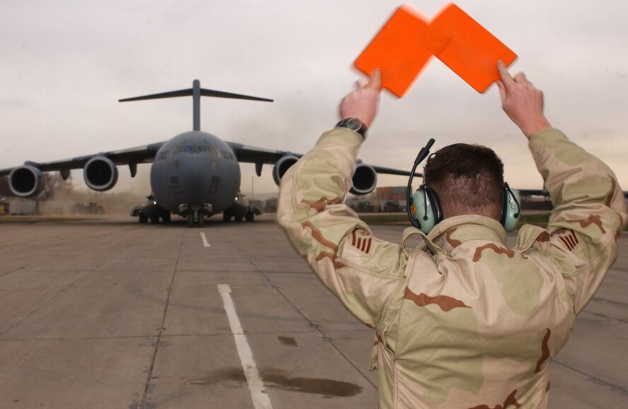 A crew chief guides in a C-17A Globemaster III carrying Secretary of Defense Donald H. Rumsfeld, at Camp Stronghold Freedom in Uzbekistan. He was there to visit troops deployed in support of Operation Enduring Freedom on Dec. 16, 2001. (U.S. Air Force photo/Staff Sgt. Steven Pearsall) 