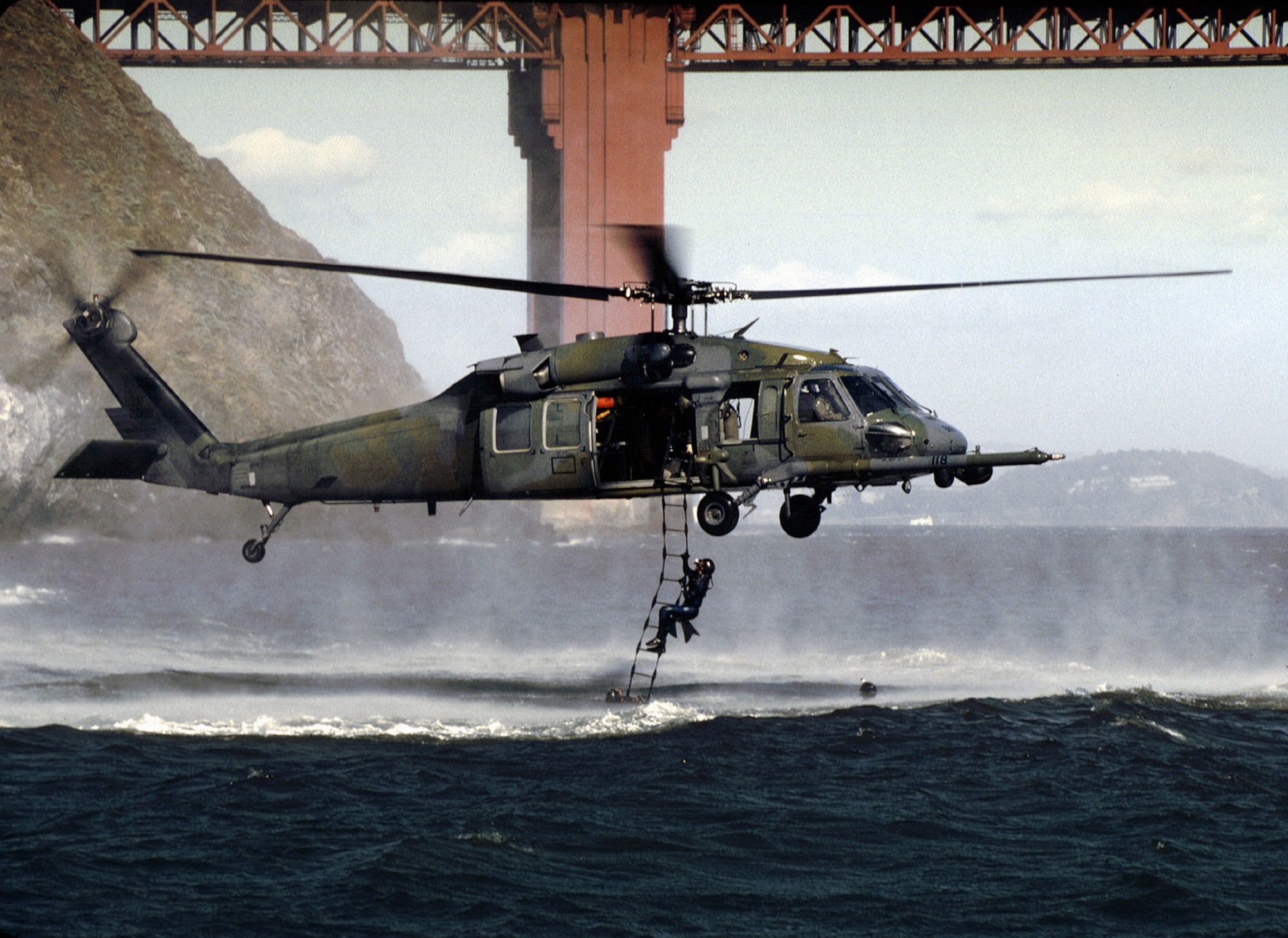 SAN FRANCISO -- California Air National Guard pararescuemen of the 129th Rescue Wing, Moffett Federal Airfield, Calif., climb up a moving rope ladder, from the chilly waters outside the Golden Gate Bridge, up to a HH-60G Pave Hawk. Tech. Sgt. Mike Sampognaro, flight engineer, monitors the training mission from the troop door. Hovering only six feet above the waves, Lt. Col. Thomas Laut must fly with extreme care as he deals with gusting winds, sea spray, sun glare, and sea swells, as he maintains a "low-and-slow" flight. Some members of the 129th provided technical assistance for the production of the movie "The Perfect Storm." (U.S. Air Force photo by Tech. Sgt. Lance Cheung)
