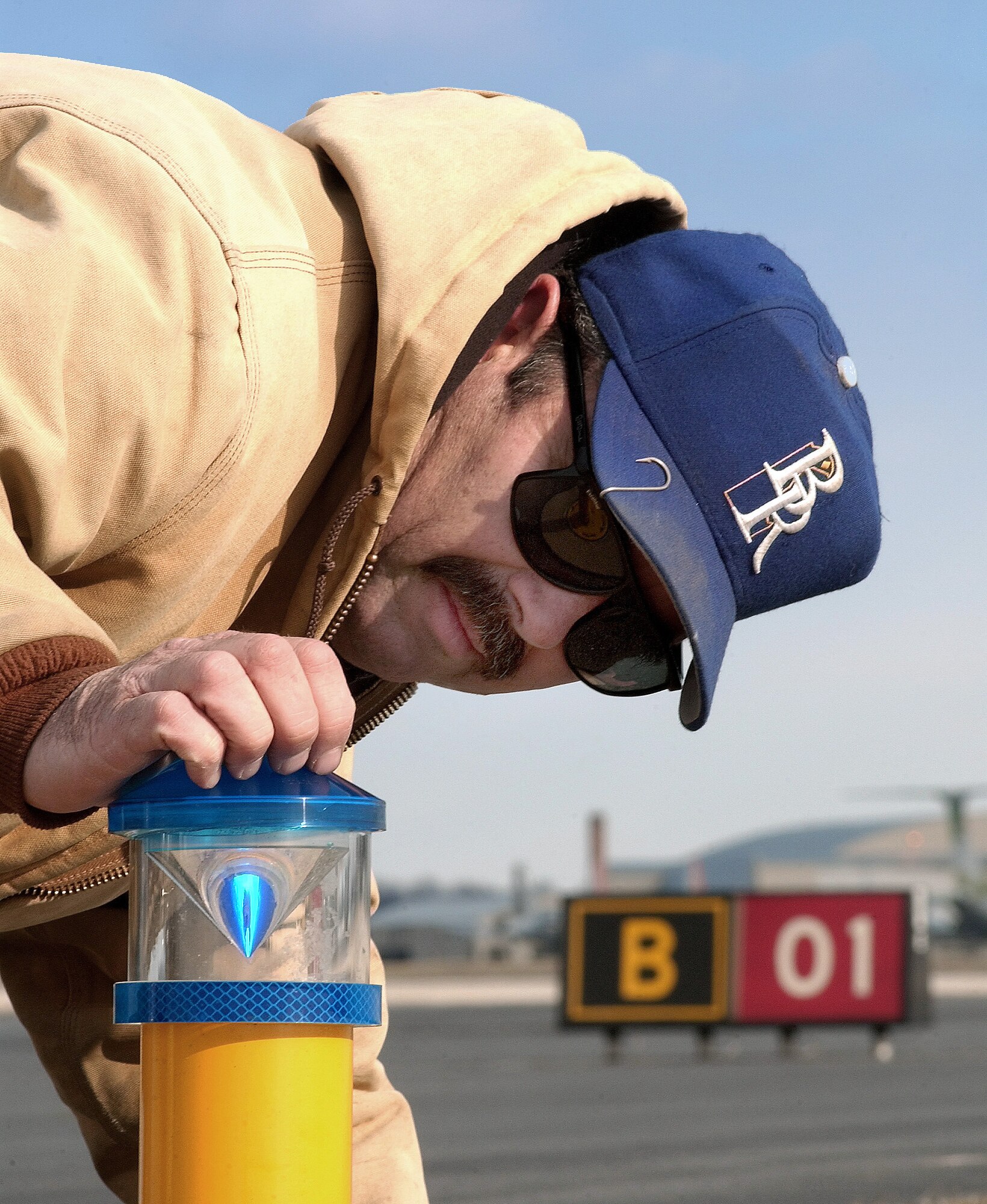 DOVER AIR FORCE BASE, Del. -- Dennis Major inspects new lights on the taxiway here. Dover is one of two Air Force installations using new diode lights that use less electricity than older models and are brighter. By design, an aircraft can hit a light and the tube will snap off the base, but the lighting unit itself will not be affected. Major works for the base's 436th Civil Engineer Squadron. (U.S. Air Force photo by William Plate Jr.)