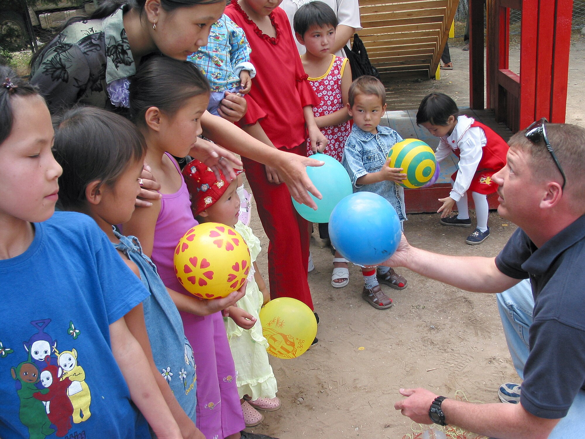 OPERATION ENDURING FREEDOM -- Master Sgt. Daniel Lester hands balls to some of the children at the playground built by airmen deployed to Ganci Air Base, Kyrgyzstan.  More than 68 airmen helped build a playground for children at the nearby Kyrgyzstan Tuberculosis Research Institute.  Lester is assigned to the 376th Expeditionary Communications Squadron at Ganci AB.  (U.S. Air Force photo by Staff Sgt. Jason Smith)
