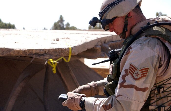 BAGHDAD, Iraq -- Staff Sgt. Tony Newbern marks the location of unexploded ordnance with a yellow ribbon and notes the coordinates using a Global Positioning System receiver.  Explosive ordnance disposal specialists traveling with the Combined Weapons Effectiveness Assessment Team in Iraq report ordnance information to an Army team for detonation.  Newbern is deployed to Iraq from Charleston Air Force Base, S.C.  (U.S. Air Force photo by Capt. Roger Burdette)