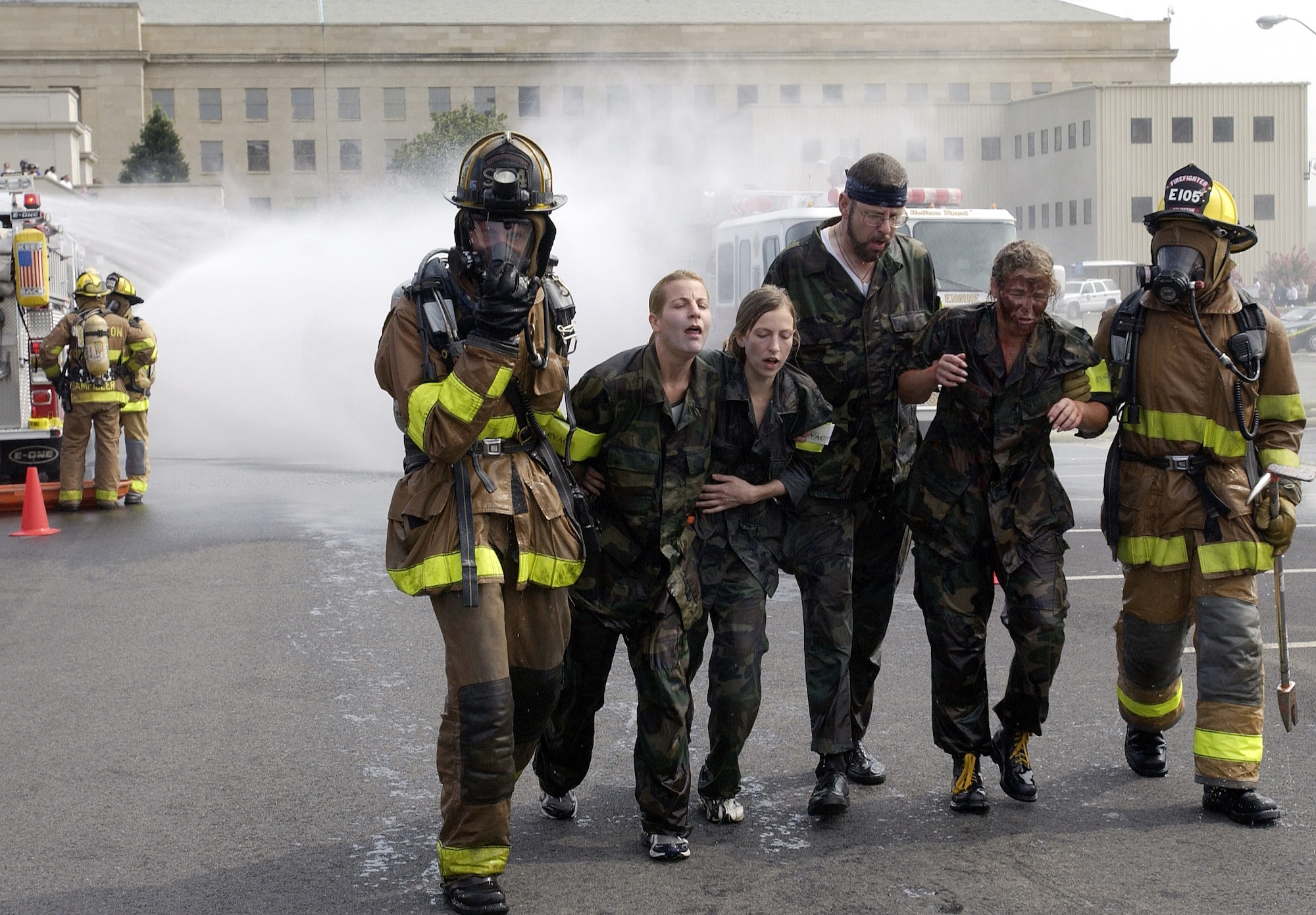 WASHINGTON -- Firefighters from Arlington County, Va., escort volunteer victims toward a simulated decontamination area in the Pentagon's south parking lot during exercise Gallant Fox on July 24.  Gallant Fox is a large-scale chemical, biological, radiological and nuclear-training exercise conducted by the Pentagon Force Protection Agency.  The exercise provides training in responding to real-world mass casualty scenarios by various local emergency fire, police, medical and hazardous-material response units.  (U.S. Air Force photo by Master Sgt. Jim Varhegyi)