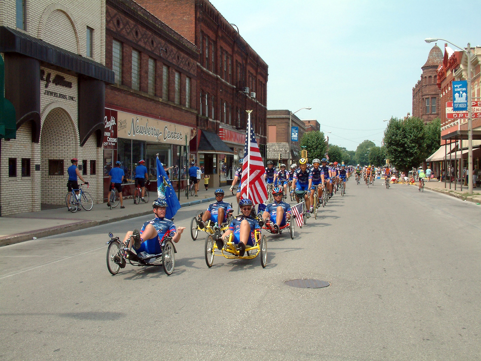 FORT MADISON, Iowa -- Staff Sgt. Brad Whitmill and Dr. Carol Belt lead the Team Air Force cyclists here July 26.  The destination marked the end of the seven-day, 450-mile Des Moines Register's Annual Great Bike Ride Across Iowa.  The American flag on Belt's bike had been recently flown over Baghdad, Iraq, and Bagram Air Base, Afghanistan.  It was carried to honor American forces serving in operations Enduring Freedom and Iraqi Freedom.  Whitmill is stationed at Offut Air Force Base, Neb., and Belt is from Scott AFB, Ill.  (U.S. Air Force photo by Master Sgt. Shawn Murphy)