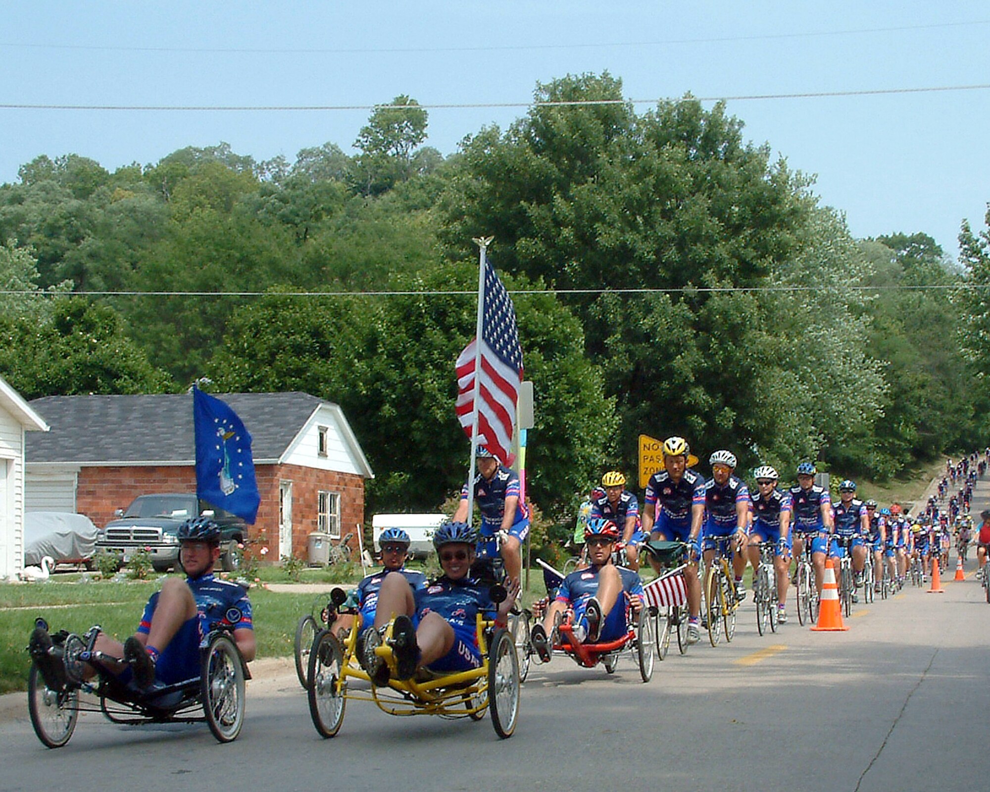 FORT MADISON, Iowa -- Staff Sgt. Brad Whitmill and Dr. Carol Belt lead the Team Air Force cyclists here July 26.  The destination marked the end of the seven-day, 450-mile Des Moines Register's Annual Great Bike Ride Across Iowa.  The American flag on Belt's bike had been recently flown over Baghdad, Iraq, and Bagram Air Base, Afghanistan.  It was carried to honor American forces serving in operations Enduring Freedom and Iraqi Freedom.  Whitmill is stationed at Offut Air Force Base, Neb., and Belt is from Scott AFB, Ill.  (U.S. Air Force photo by Master Sgt. Shawn Murphy)