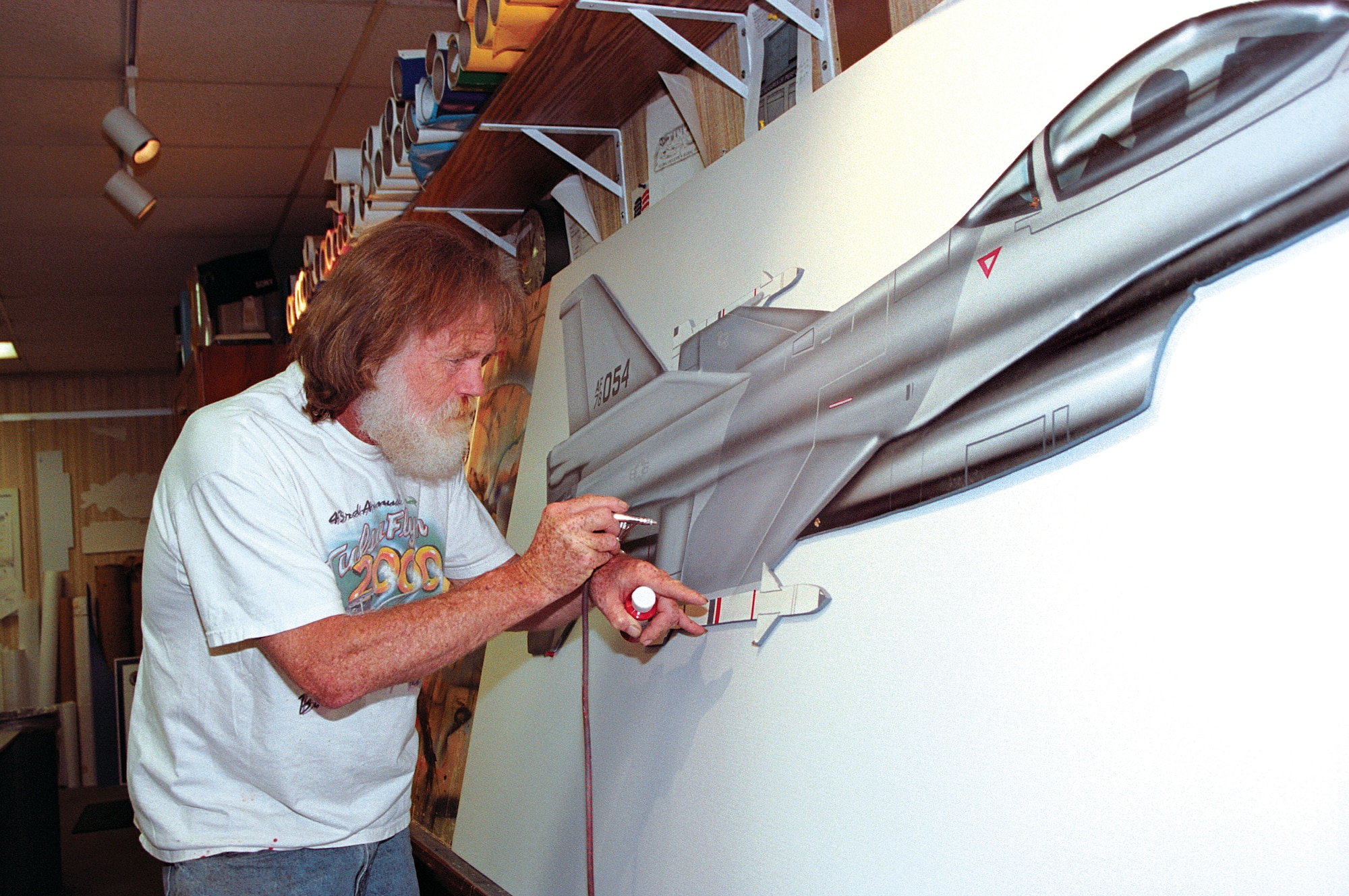 TINKER AIR FORCE BASE, Okla. -- R.T. Foster airbrushes an illustration of an F-16 Fighting Falcon.  Three paintings by the longtime illustrator here are on permanent display at the Oklahoma state capital, and his work also hangs in galleries from the Smithsonian Air and Space Museum to the San Diego Air and Space Museum.  (Courtesy photo)