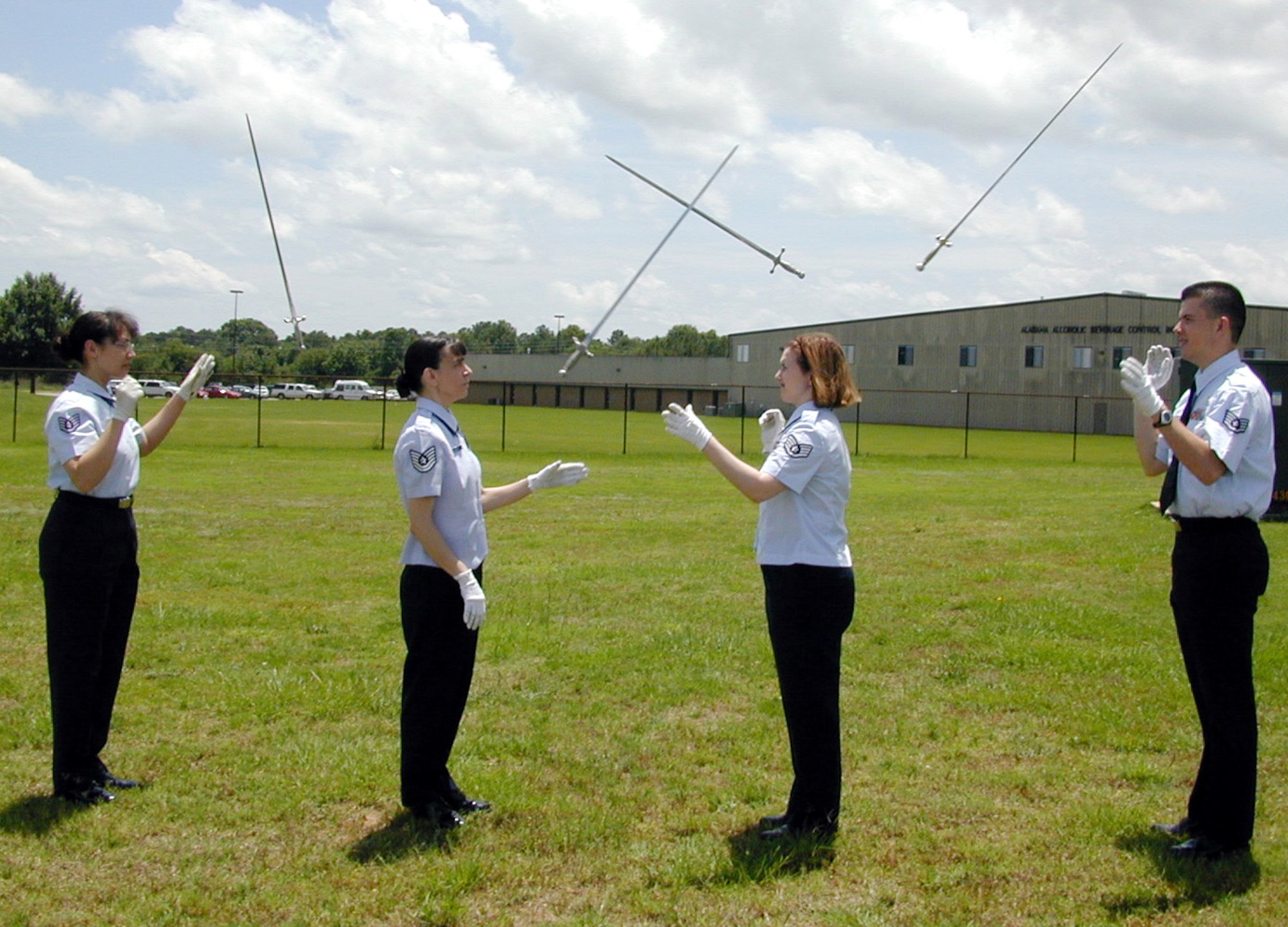 GUNTER ANNEX, Ala. (AFPN) -- (Left to right) Staff Sgt. Jennifer Kelley, Tech. Sgt. Tracey Ulanski, Staff Sgt. Amanda Stoll and Staff Sgt. Jared Sledge perform an overhead toss, where the four members toss their sabers into the air diagonally then catch the sabers one-handed.  (U.S. Air Force photo by Belinda Bazinet)
