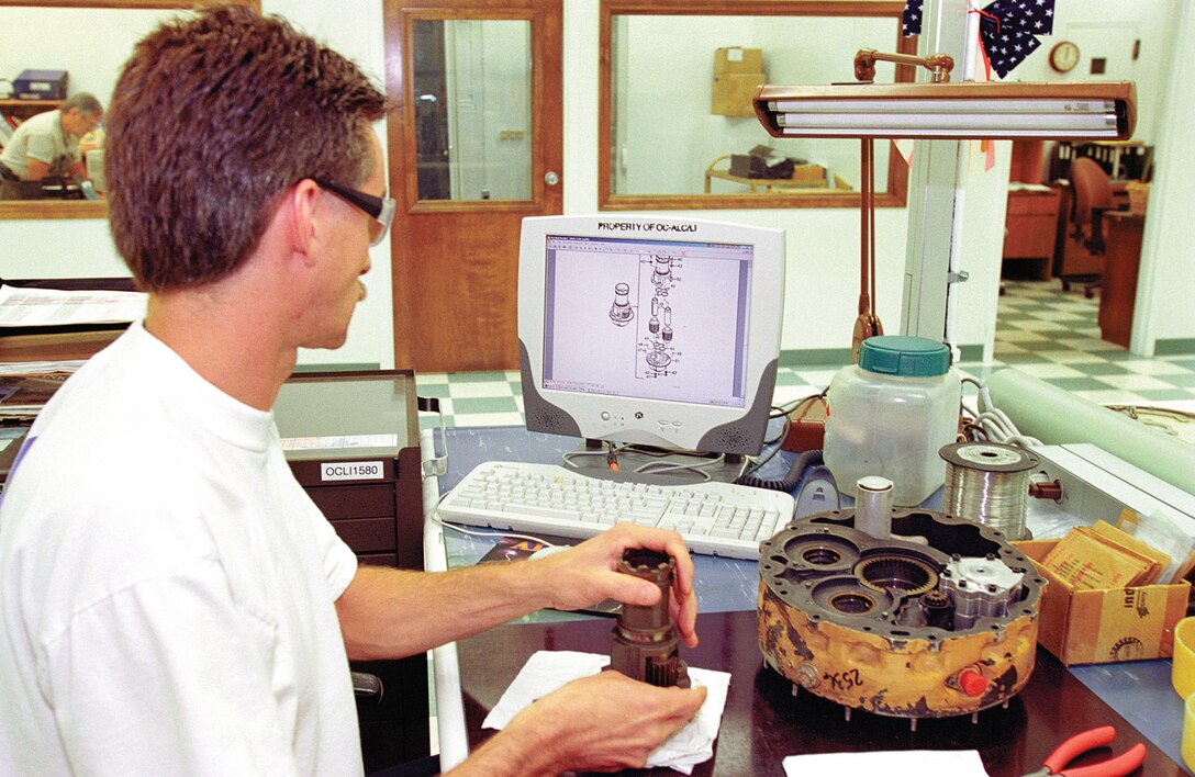 TINKER AIR FORCE BASE, Okla. (AFPN) -- Chris Caldwell, a pneudraulics mechanic, reviews a technical order on his computer monitor while rebuilding an F-15 Eagle part.  An online TO library puts the latest technical orders a mouse-click away from each of the 10,000 or so mechanics at the Oklahoma City Air Logistics Center here. (U.S. Air Force photo by Margo Wright)