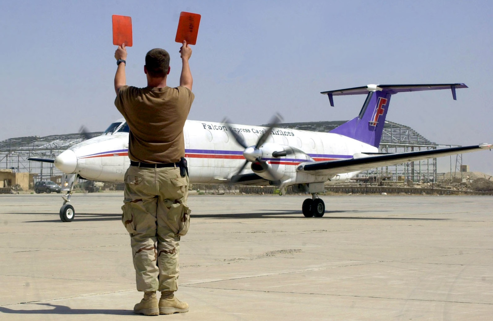 TALLIL AIR BASE, Iraq (AFPN) -- Staff Sgt. Christopher Chandler marshals in the first commercial aircraft to land here.  The Beechcraft 1900 turbo-prop landed here June 12 and is operated by Falcon Express Cargo of Dubai, United Arab Emirates.  Chandler is assigned to the 407th Expeditionary Logistics Readiness Squadron's transient alert crew.  (U.S. Air Force photo by Master Sgt. Deb Smith)