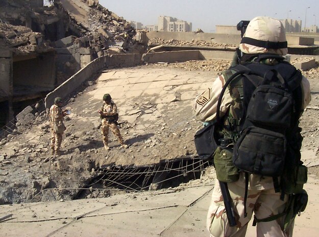 BAGHDAD, Iraq -- Members of the Combined Weapons Effectiveness Assessment Team collect information as Master Sgt. Michael Best, foreground, photographs an impact point where a coalition weapon entered the top of an Iraqi Ministry of Defense building here.  Best is a combat-camera photographer deployed from Charleston Air Force Base, S.C.  (U.S. Air Force photo by Capt. Roger Burdette)