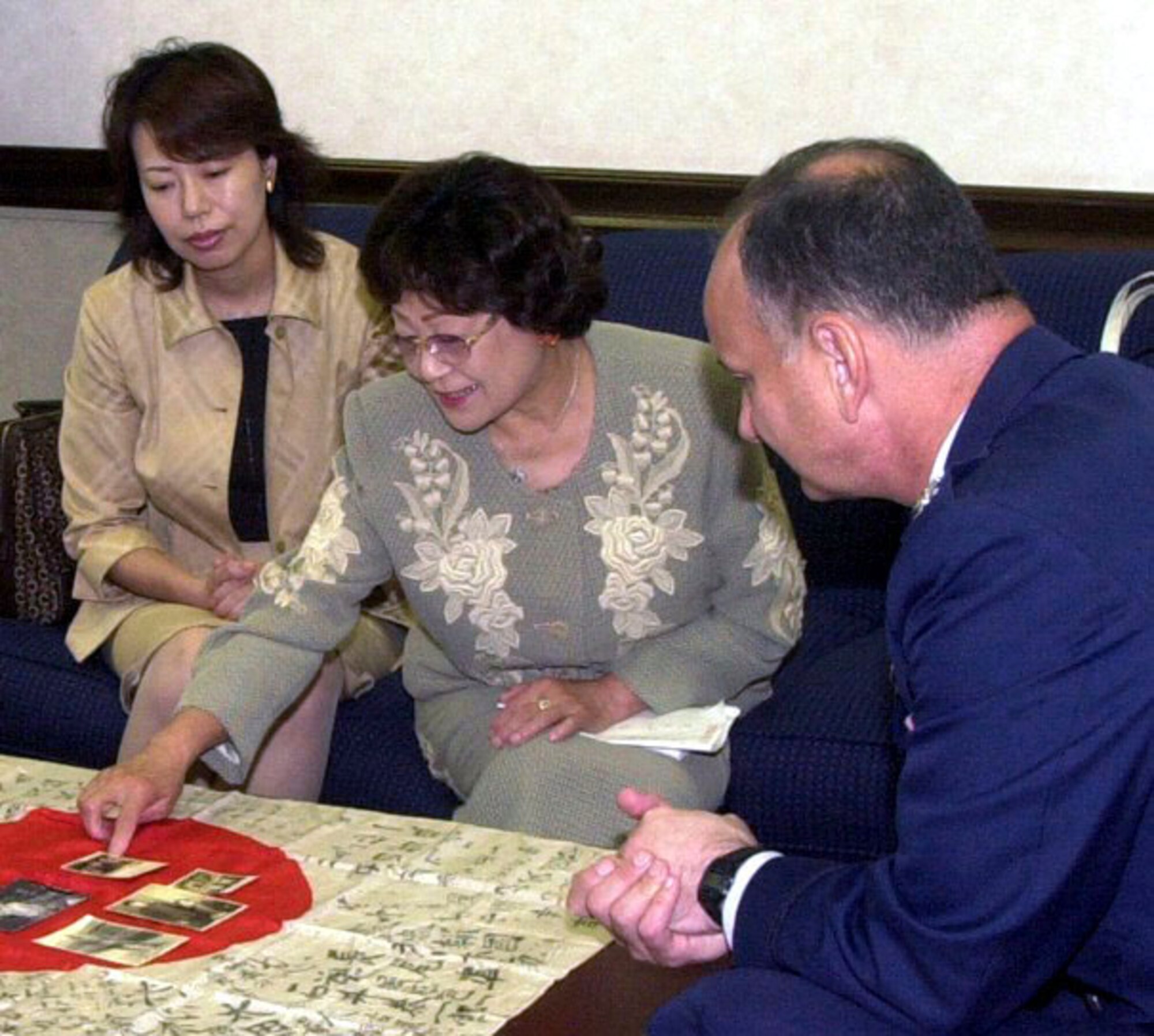 YOKOTA AIR BASE, Japan (AFPN) -- Reiko Motegi shows Col. Don Weckhorst photos of her late husband, Mototeru Motegi, who served in the Japanese military during World War II.  Weckhorst presented a Japanese flag to Motegi and her daughter, Yoshimi Morita.  The flag was carried into battle by Motegi's husband and it disappeared nearly 60 years ago.  A collector gave the flag to Weckhorst's father in an attempt to return it to the soldier's family.  Weckworst is the commander of the 605th Air Operations Group here.  (U.S. Air Force photo by Airman 1st Class Heather Norris)