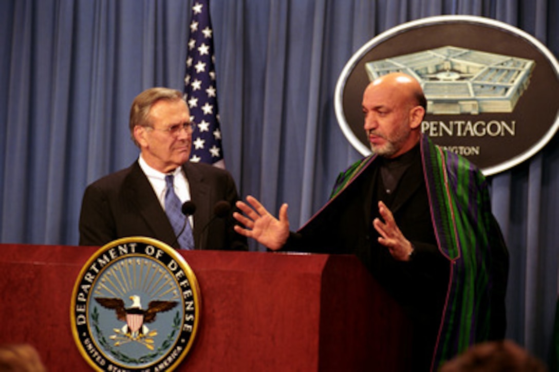 Secretary of Defense Donald H. Rumsfeld (left) listens as Afghan President Hamid Karzai responds to a reporter's question during a joint press conference in the Pentagon on Feb. 27, 2003. Rumsfeld and Karzai met earlier to discuss defense issues of mutual interest and the future of Afghanistan. 