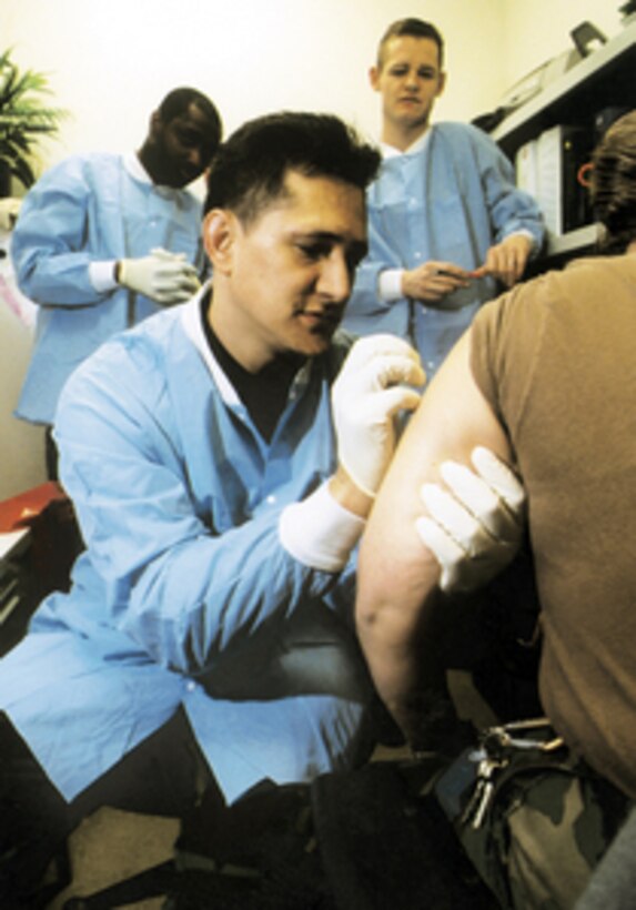 Air Force Master Sgt. Ray Anspach immunizes a soldier against smallpox at Walter Reed Army Medical Center as other medical technicians observe the technique on Jan. 14, 2003. Anspach is using a bifurcated or forked needle to administer the vaccine. 
