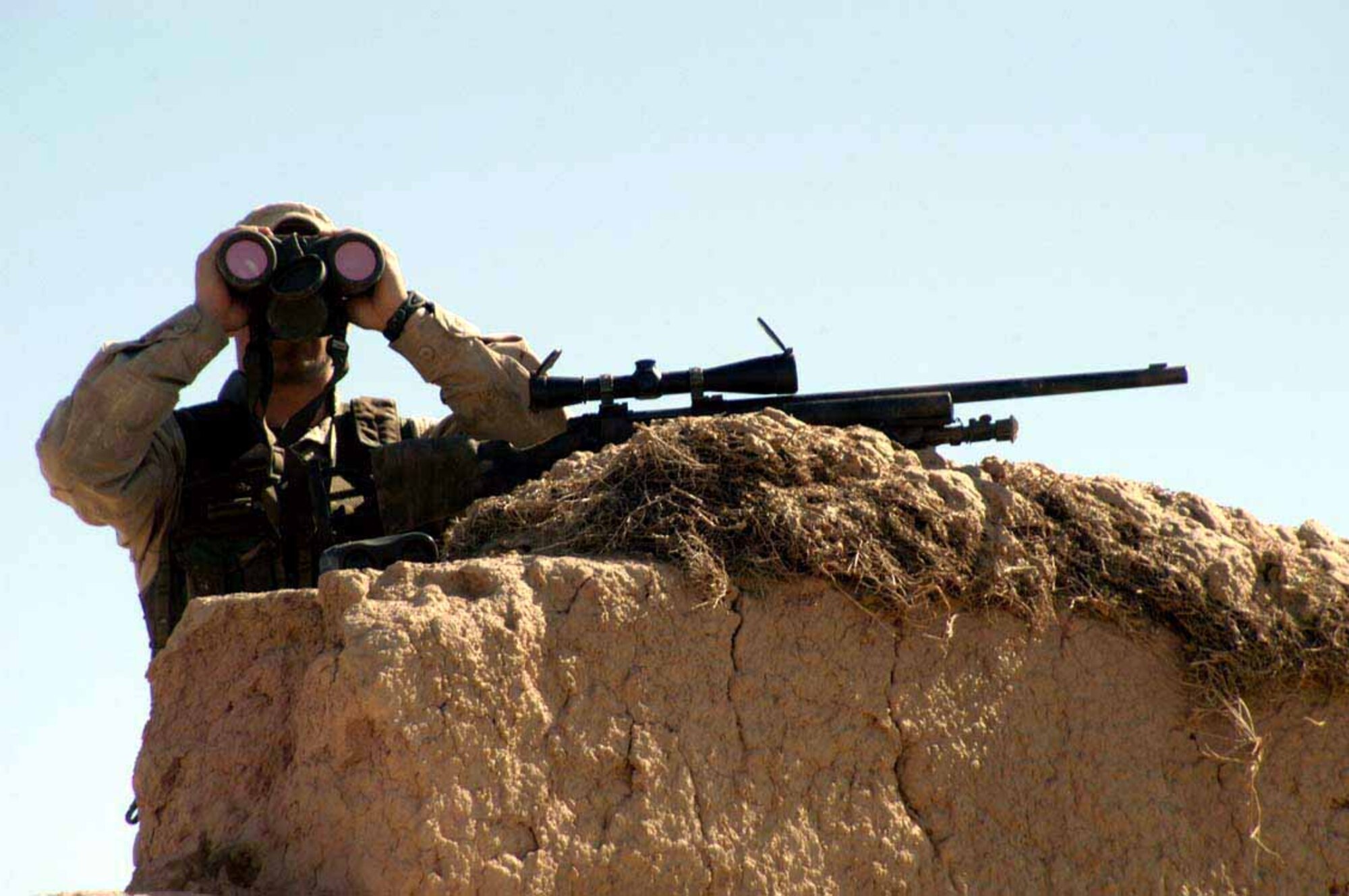 OPERATION ENDURING FREEDOM -- Airman 1st Class Brandon White scans the horizon for potential adversaries atop a wall in the city of Qal'eh-ye Musa Pa-in, Afghanistan, on March 12 during a special delivery to the village. White, who is deployed from Moody Air Force Base, Ga., was on the wall as part of a security detail as 20 airmen delivered more than 750 pounds of school supplies, clothing, shoes and food to about 50 families. The donations were mailed to airmen from friends, relatives and church groups. The airman is a fire team member assigned to the 455th Expeditionary Security Forces Squadron. (U.S. Air Force photo by Tech. Sgt. Adam Johnston)