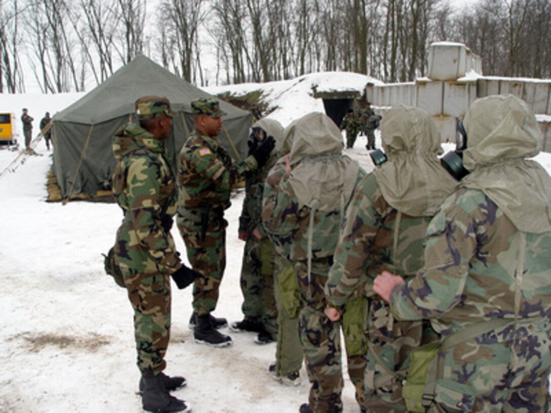 U.S. Army Staff Sgt. James Williams (left) watches as Staff Sgt. Caul Debose (center) checks the seal of a protective mask for a Free Iraqi Forces volunteer during training at Taszar Air Base, Hungary, on March 10, 2003. Soldiers from 31 units across the U.S. Army are training Iraqi opposition volunteers, provided by the Iraqi Opposition Groups, on developing skills in civil military operations to assist coalition forces in coordinating humanitarian relief efforts and other civil support functions. Williams and Debose are drill sergeants with the Army's 1st Battalion, 61st Infantry, Fort Jackson, S.C. 