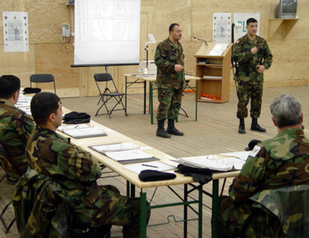 Staff Sgt. Rene Fournier (right) instructs Free Iraqi Forces volunteers with the aid of a translator at Taszar Air Base, Hungary, on March 10, 2003. Soldiers from 31 units across the U.S. Army are training Iraqi opposition volunteers, provided by the Iraqi Opposition Groups, on developing skills in civil military operations to assist coalition forces in coordinating humanitarian relief efforts and other civil support functions. Fournier is deployed to Taszar from the U.S. Army's Noncommissioned Officer Academy at Fort Knox, Ky. 