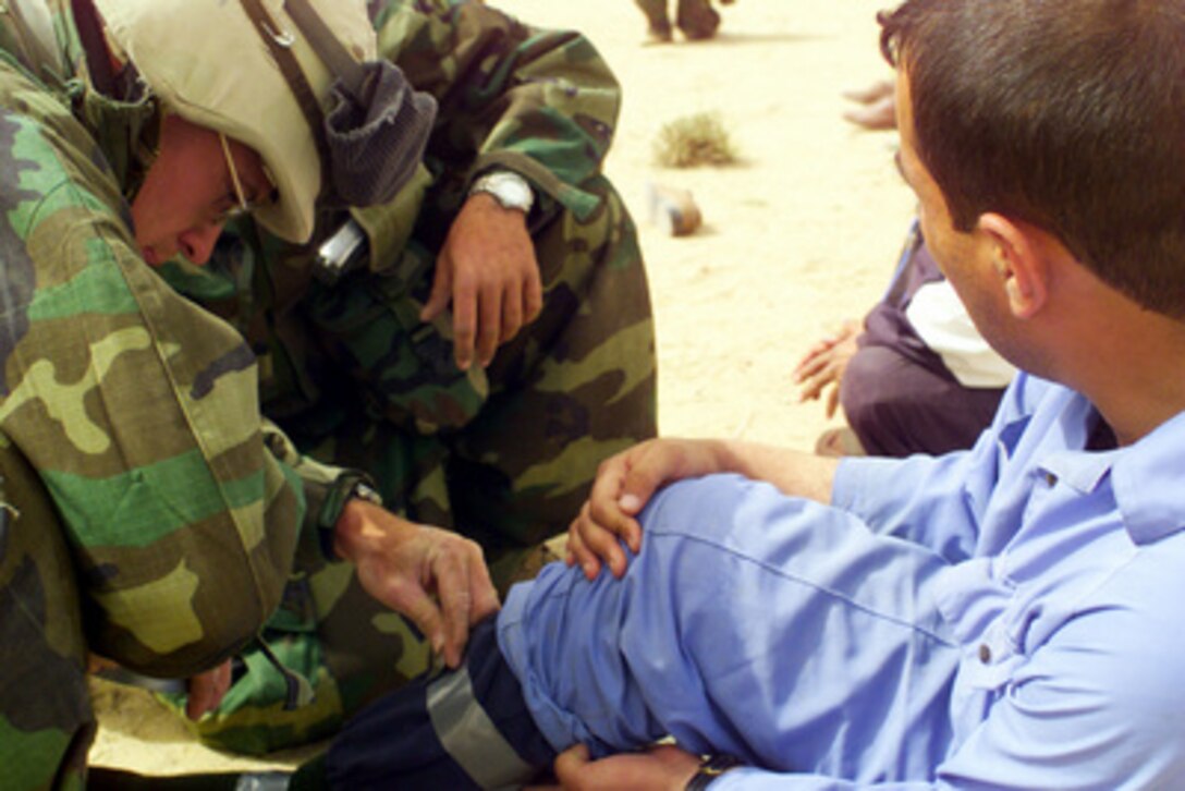 U.S. Marines from the 2nd Battalion, 1st Marine Regiment assist a captured enemy prisoner of war in the desert of Iraq on March 21, 2003, during Operation Iraqi Freedom. Operation Iraqi Freedom is the multinational coalition effort to liberate the Iraqi people, eliminate Iraq's weapons of mass destruction and end the regime of Saddam Hussein. 