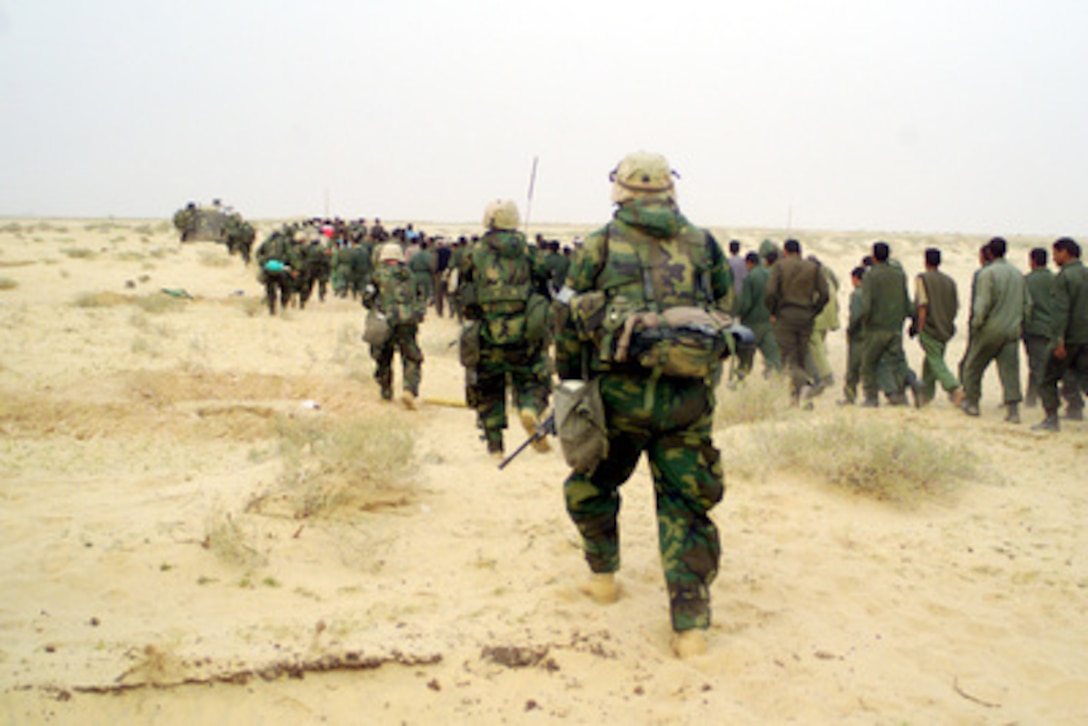 U.S. Marines from the 2nd Battalion, 1st Marine Regiment escort captured enemy prisoners of war to a holding area in the desert of Iraq on March 21, 2003, during Operation Iraqi Freedom. Operation Iraqi Freedom is the multinational coalition effort to liberate the Iraqi people, eliminate Iraq's weapons of mass destruction and end the regime of Saddam Hussein. 