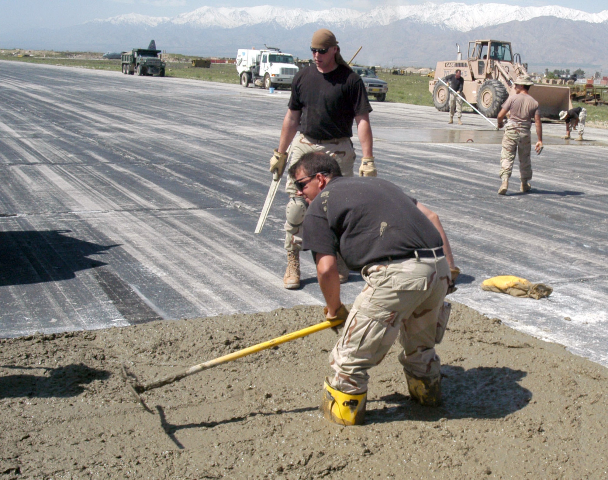 OPERATION ENDURING FREEDOM (AFPN) -- Tech. Sgt. James Holman spreads concrete in a hole on the active runway at Bagram Air Base, Afghanistan, as part of a $2.3 million airfield repair project.  Holman is deployed form the 48th Civil Engineer Squadron at Royal Air Force Lakenheath, England.  (U.S. Air Force photo by Tech. Sgt. Adam Johnston)