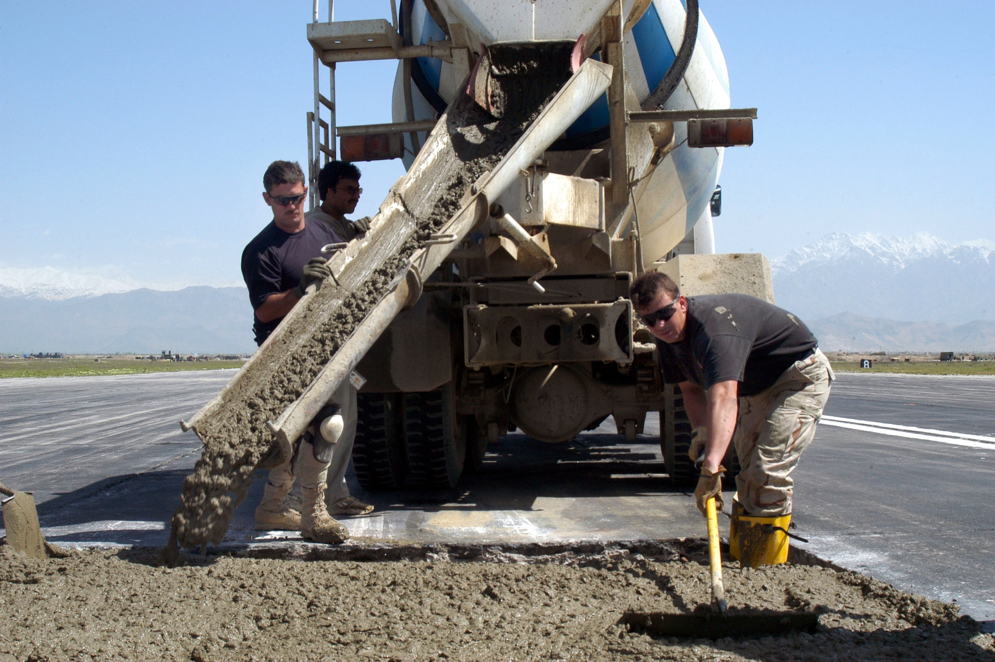OPERATION ENDURING FREEDOM (AFPN) -- Tech. Sgt. John Foster (left) pours concrete on the active runway at Bagram Air Base, Afghanistan, as part of a $2.3 million airfield repair project.  Tech. Sgt. James Holman spreads concrete in a hole.  Foster is the runway repair project manager with the 455th Expeditionary Operations Group civil engineer element. He is deployed from the 18th Civil Engineer Squadron at Kadena Air Base, Japan. Holman is from the 48th Civil Engineer Squadron at Royal Air Force Lakenheath, England.  (U.S. Air Force photo by Tech. Sgt. Adam Johnston)