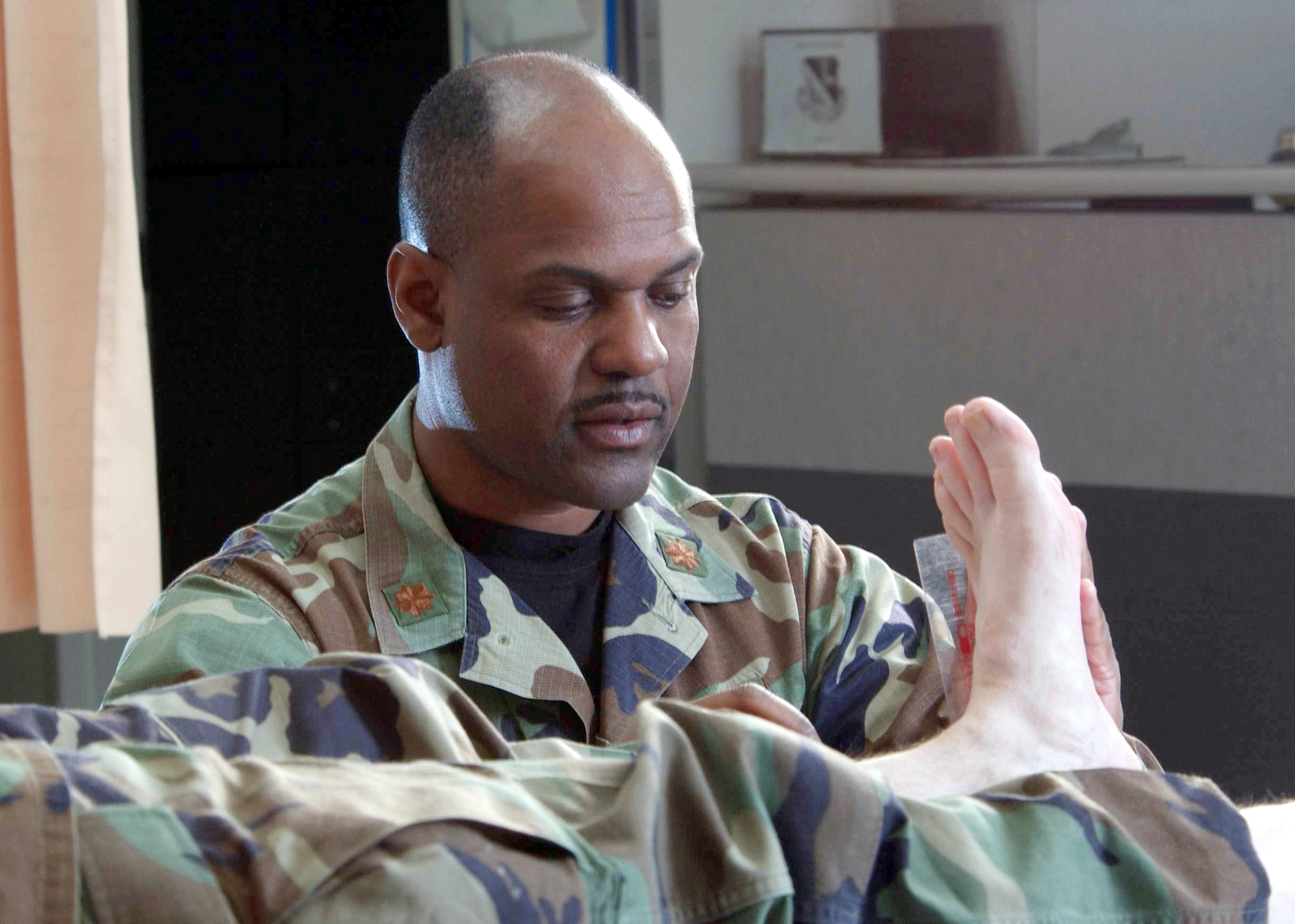 YOKOTA AIR BASE, Japan -- Maj. Raymond Bailey examines a patient's foot during rehabilitation treatment.  Bailey is a physical therapist from the 374th Medical Group here.  The physical therapy element provides services that help restore function, improve mobility, relieve pain and prevent or limit disabilities of thousands of patients each year. (U.S. Air Force photo by Master Sgt. Val Gempis)