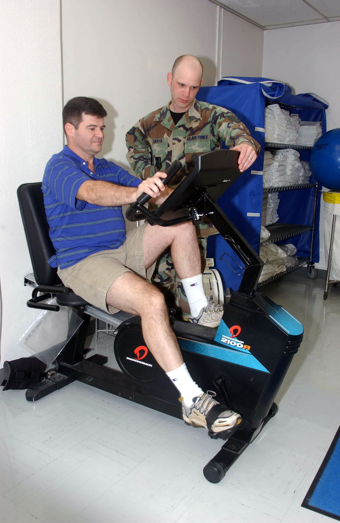 YOKOTA AIR BASE, Japan -- Staff Sgt Dan Davis observes while Chaplain (Capt.) John Tillery rides a bike during his rehabilitation treatment.  Davis is a physical therapy technician from the 374th Medical Group here.  The physical therapy element provides services that help restore function, improve mobility, relieve pain and prevent or limit disabilities of thousands of patients each year. (U.S. Air Force photo by Master Sgt. Val Gempis)